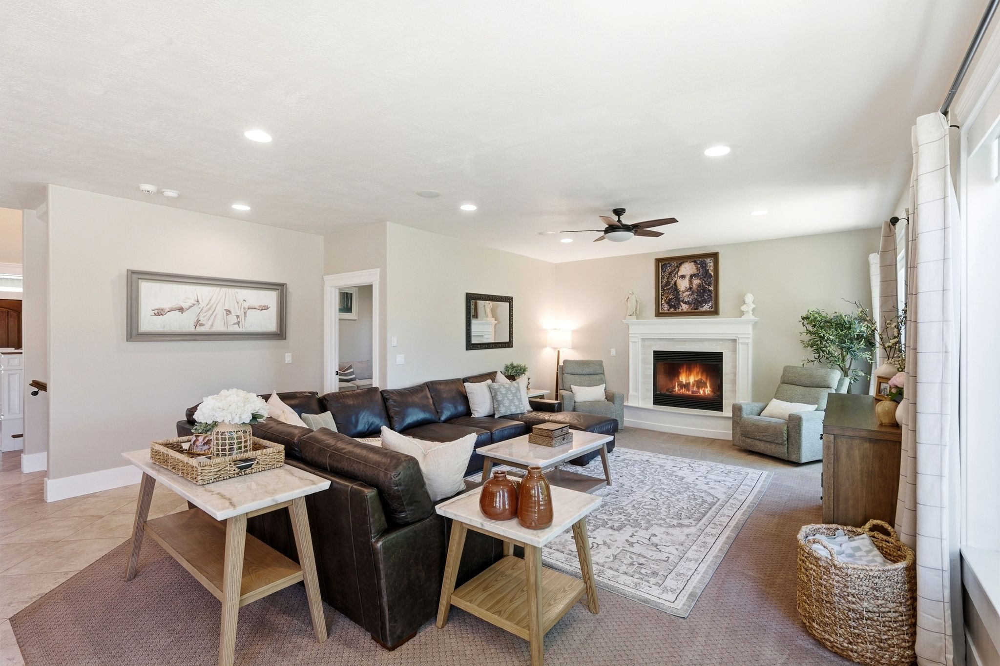 Spacious living area featuring a central fireplace with a white mantel, recessed lighting, and a ceiling fan