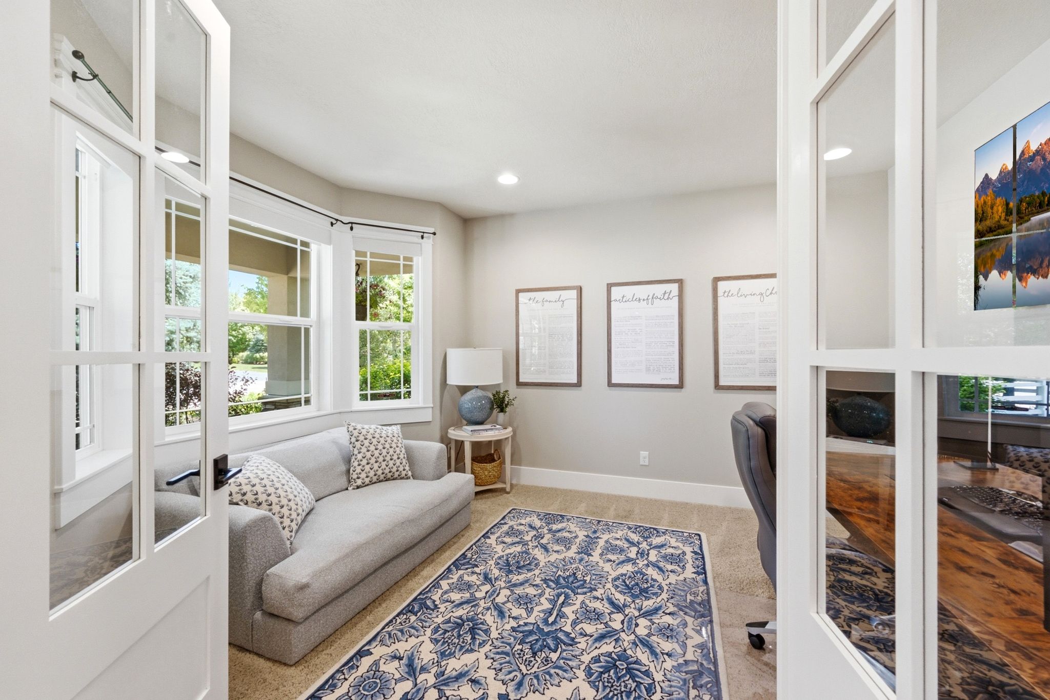 French doors opening to a versatile room featuring a bay window, neutral wall paint, and beige carpeting