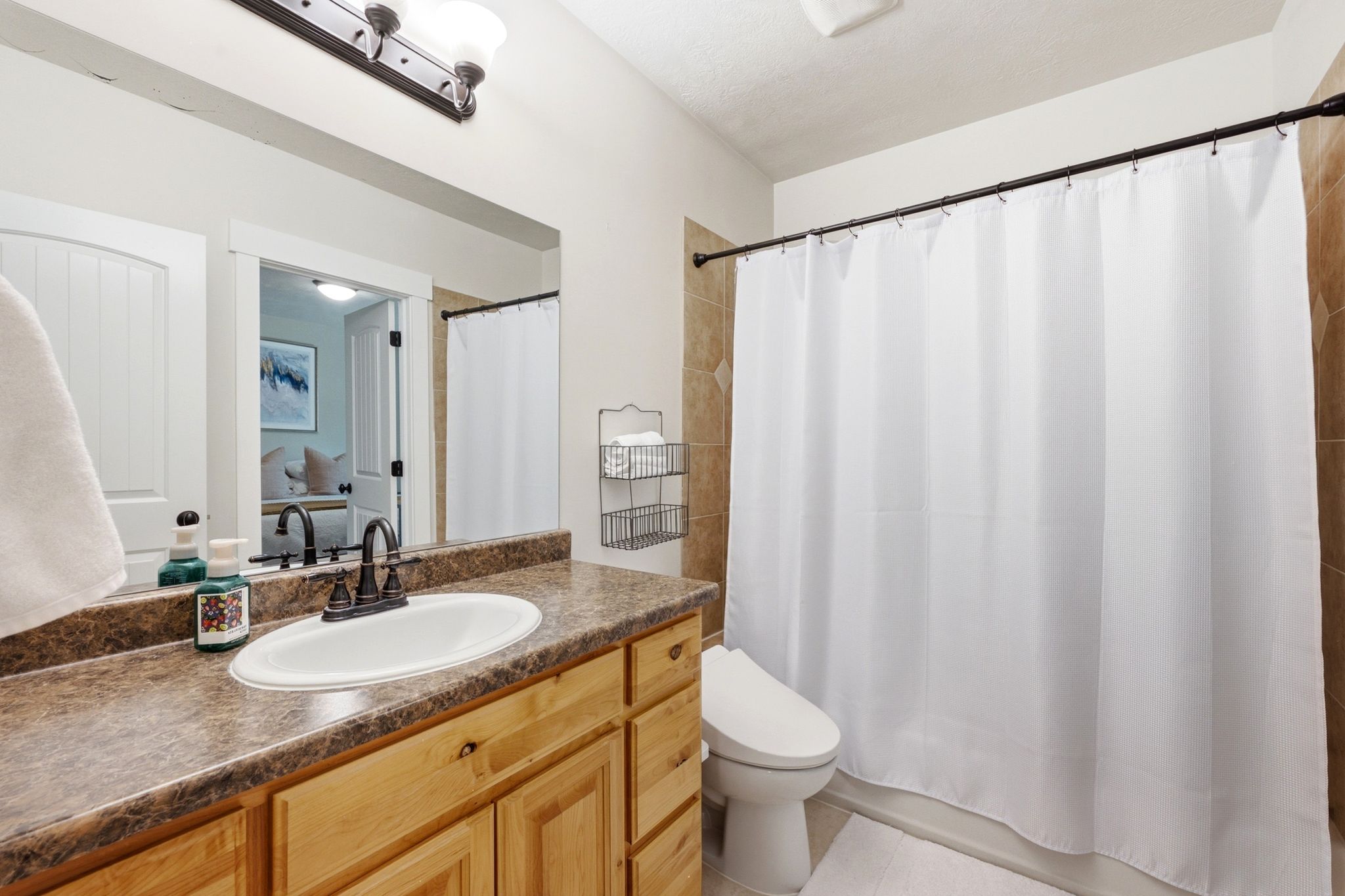 Bathroom featuring a wood-finish vanity with an oval sink, dark countertop, and oil-rubbed bronze faucet