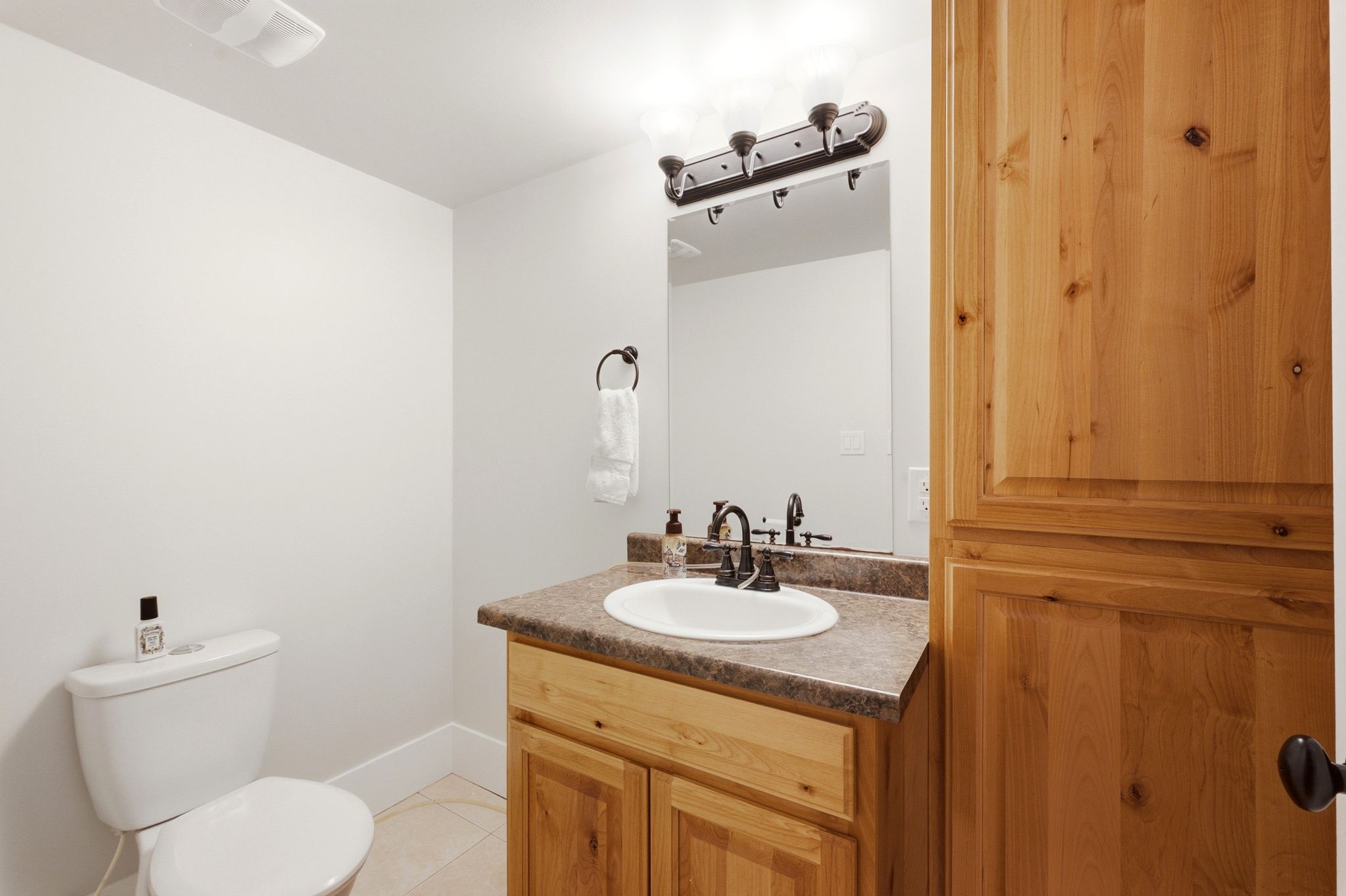 Bathroom featuring a wood-finish vanity with an integrated sink and a speckled countertop