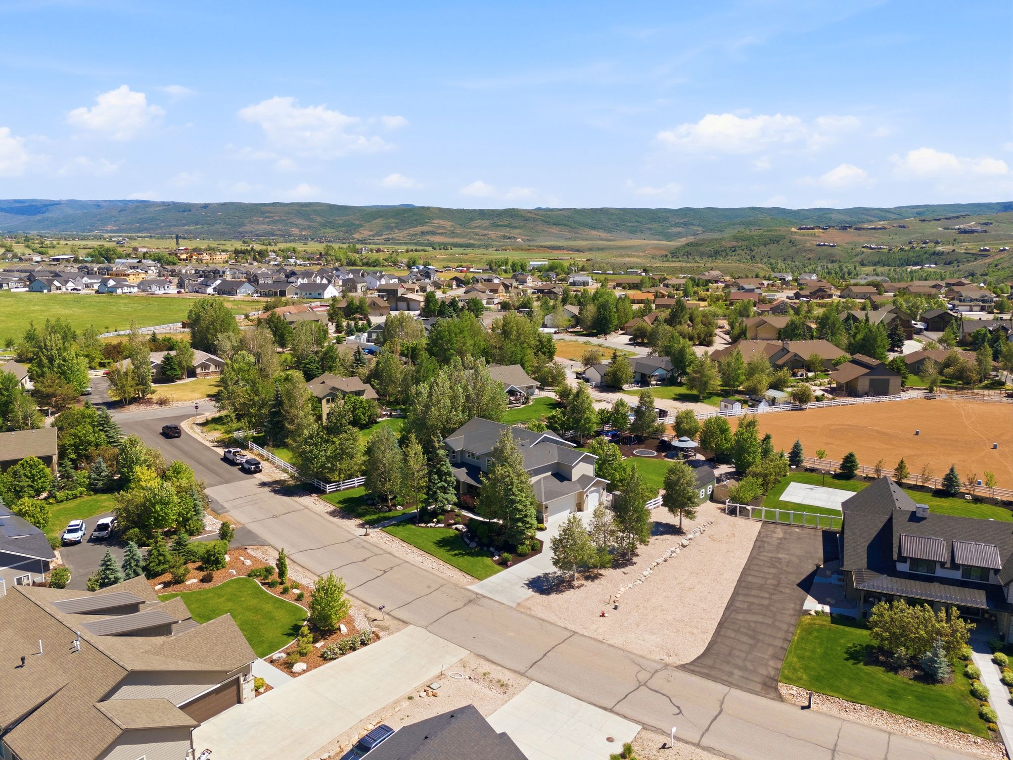 Residential neighborhood featuring diverse architectural styles, mature trees, manicured lawns, and paved streets