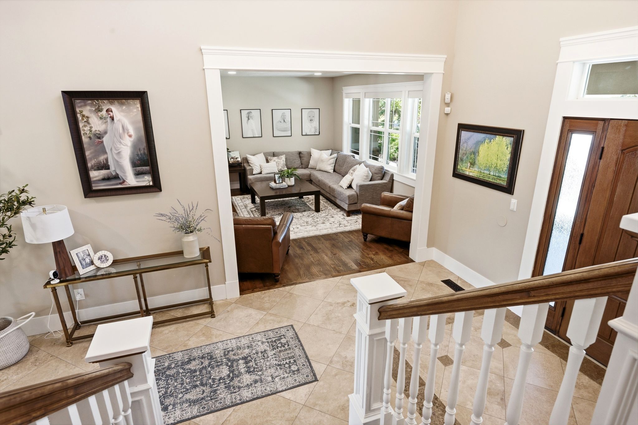 Spacious entryway featuring tile flooring with decorative inserts and a wooden handrail with white balusters