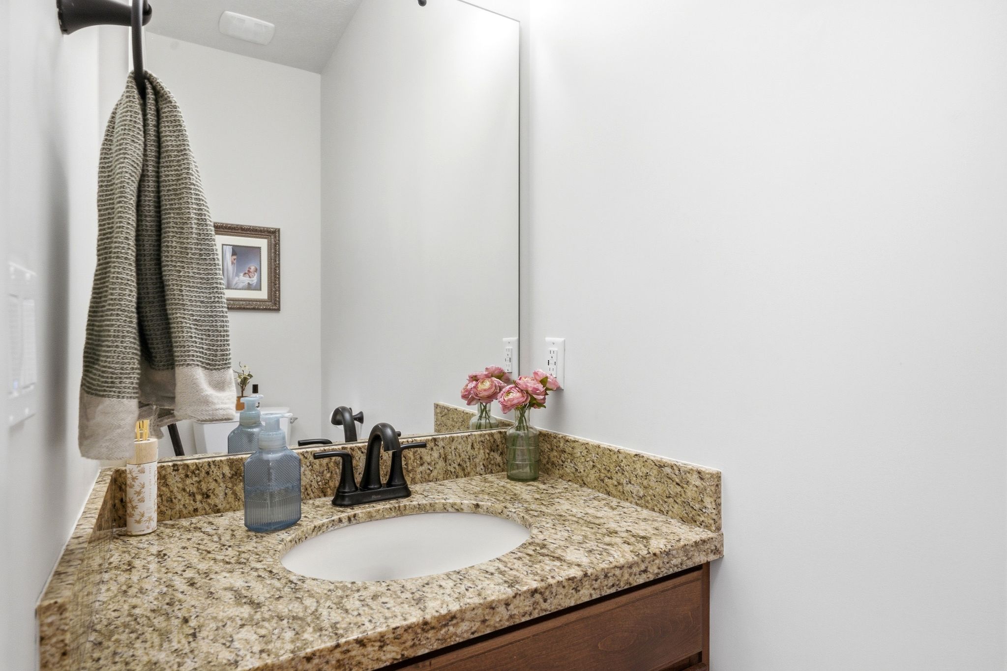 Bathroom vanity featuring a granite countertop, integrated sink, and dark bronze-finish faucet