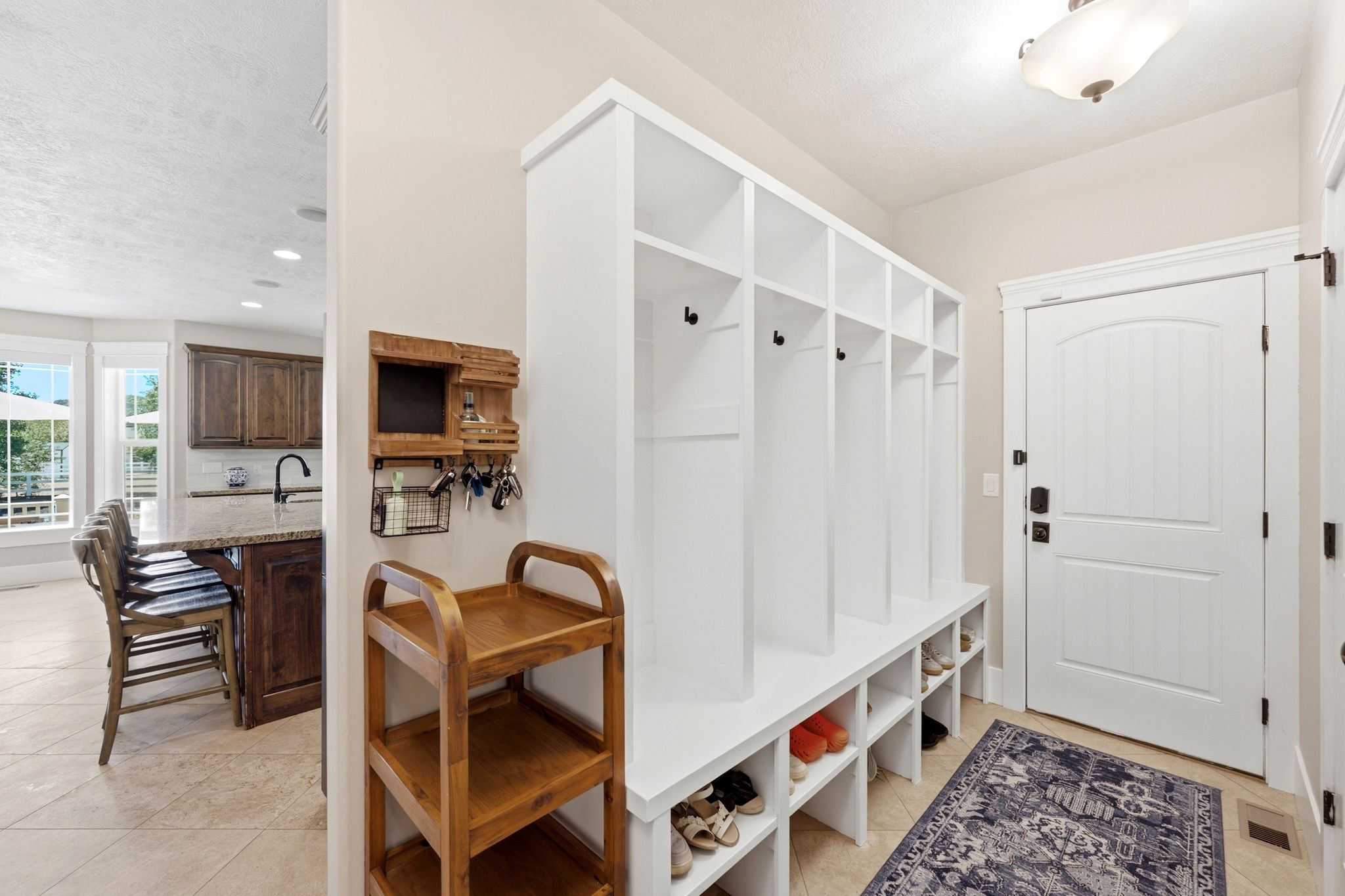 Entryway featuring a built-in white storage system with hooks and integrated shoe cubbies