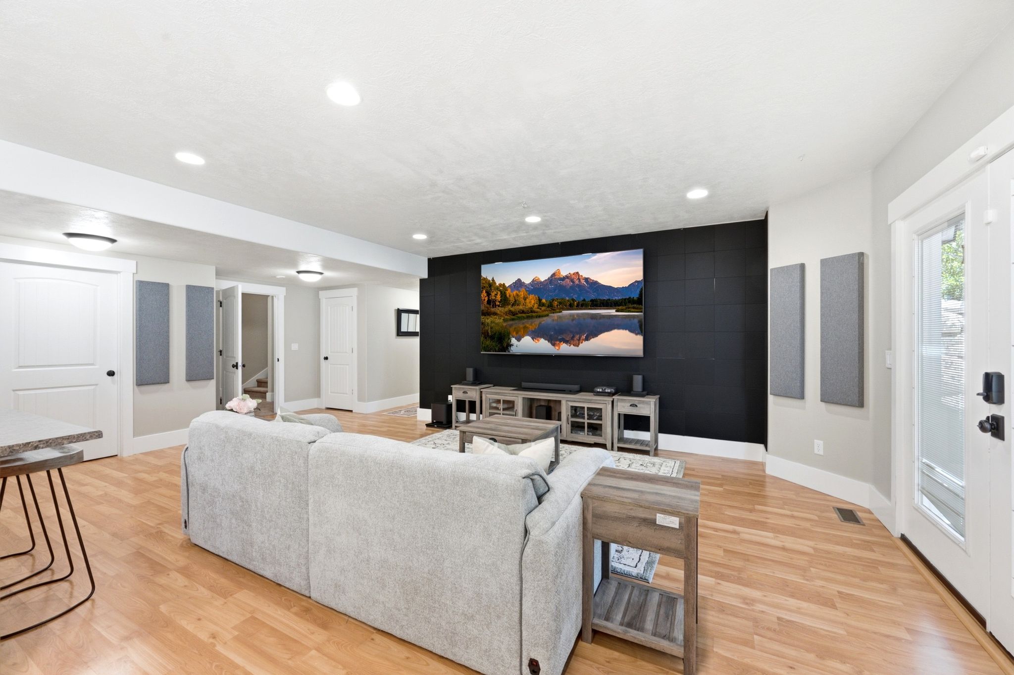 Open-concept living area featuring wood-finish flooring, recessed lighting, and a textured accent wall