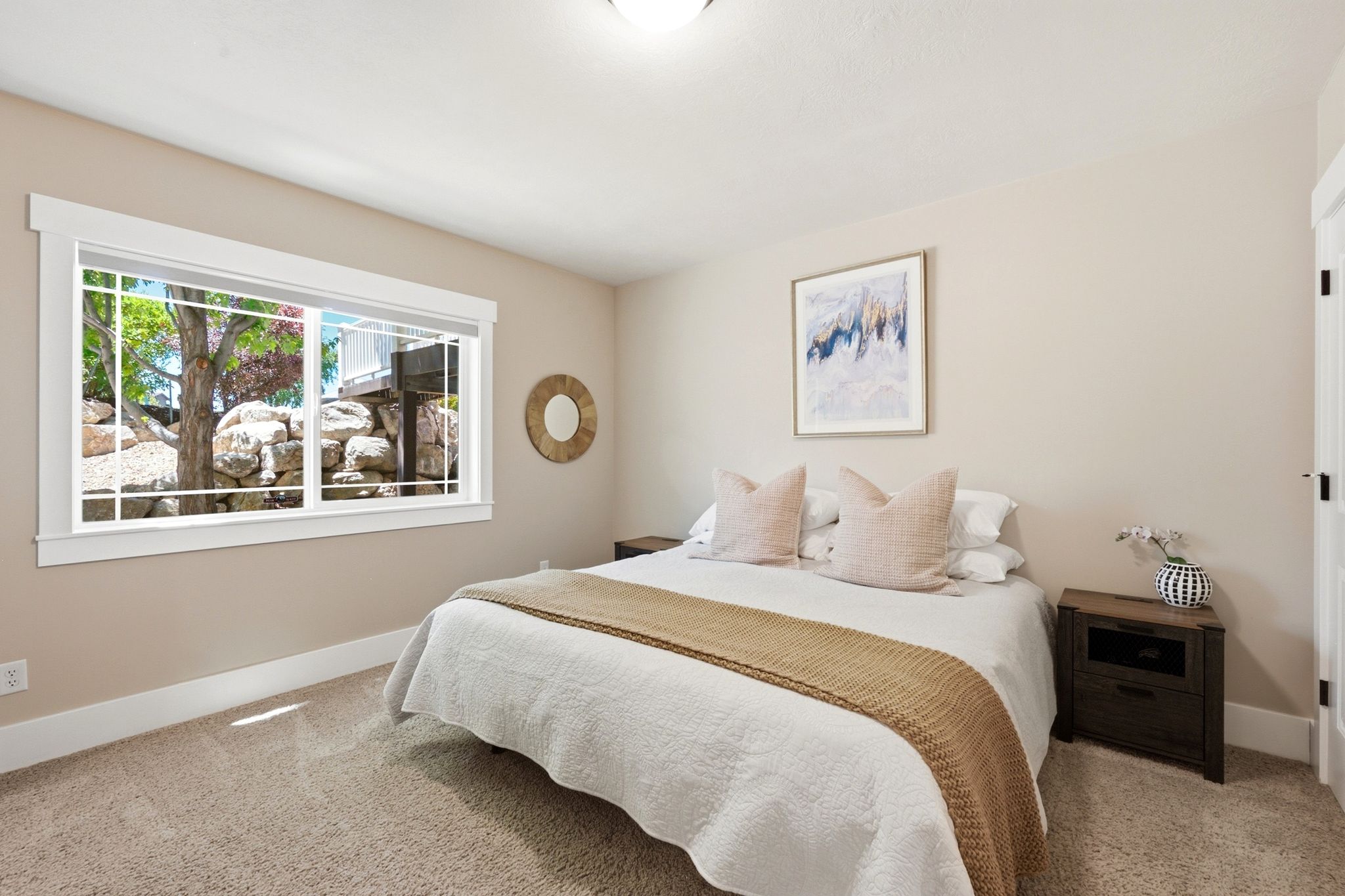 Spacious bedroom featuring neutral wall tones, plush carpet flooring, a large window with white grilles, and white trim throughout