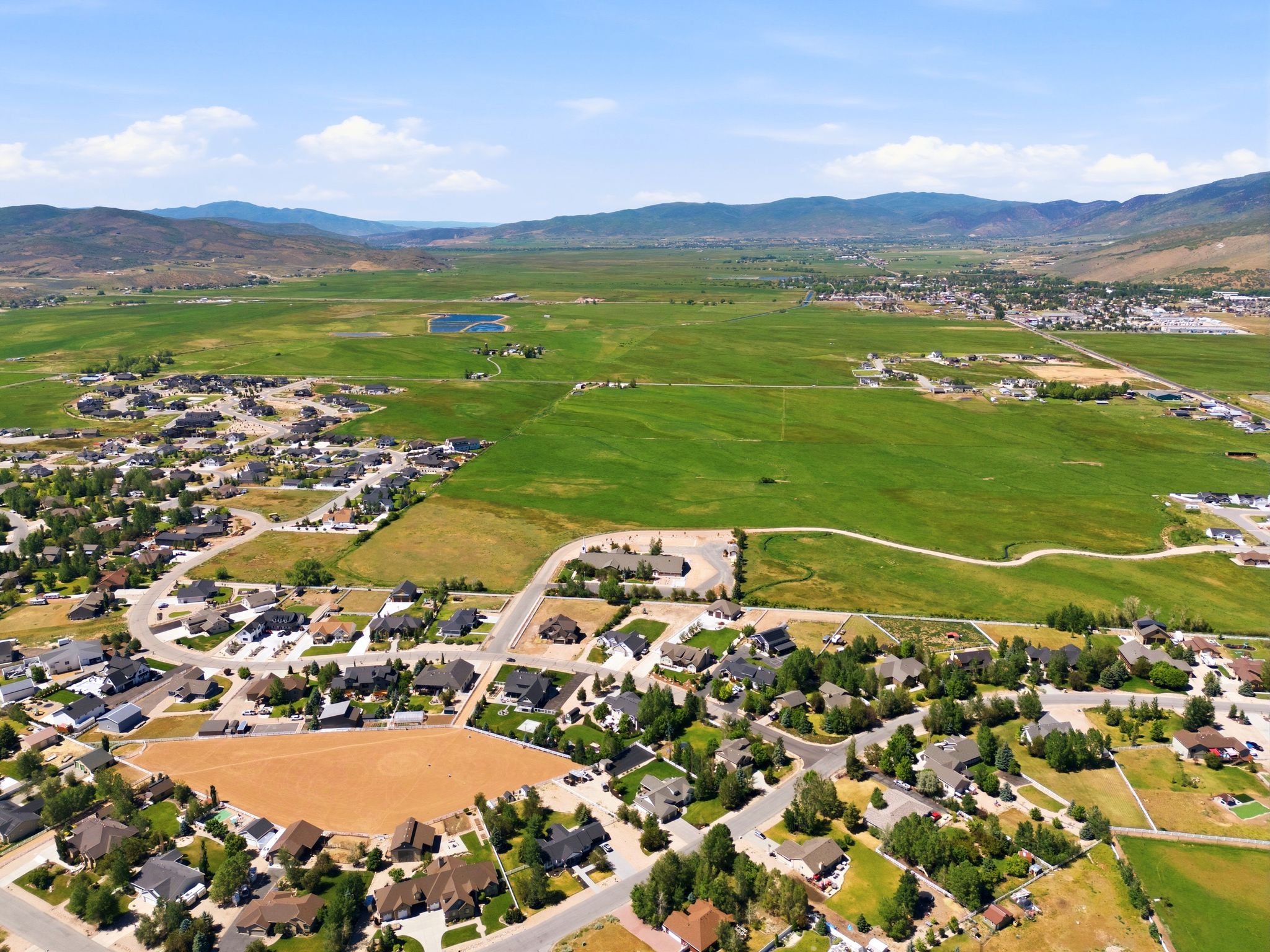 Expansive rural landscape featuring a residential community with abundant green spaces and distant mountains