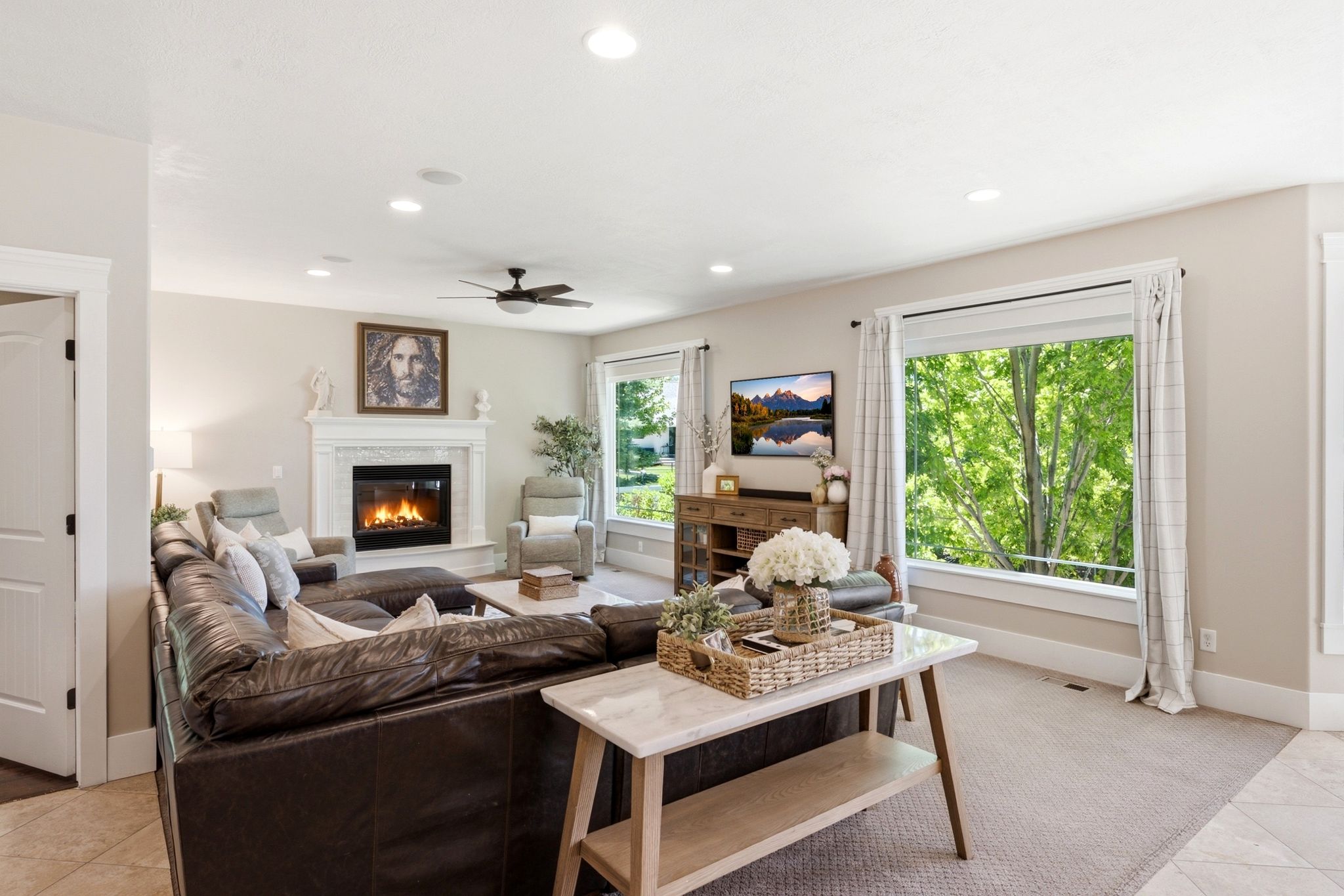 Spacious living area featuring a fireplace with a white mantel, recessed lighting, and a ceiling fan