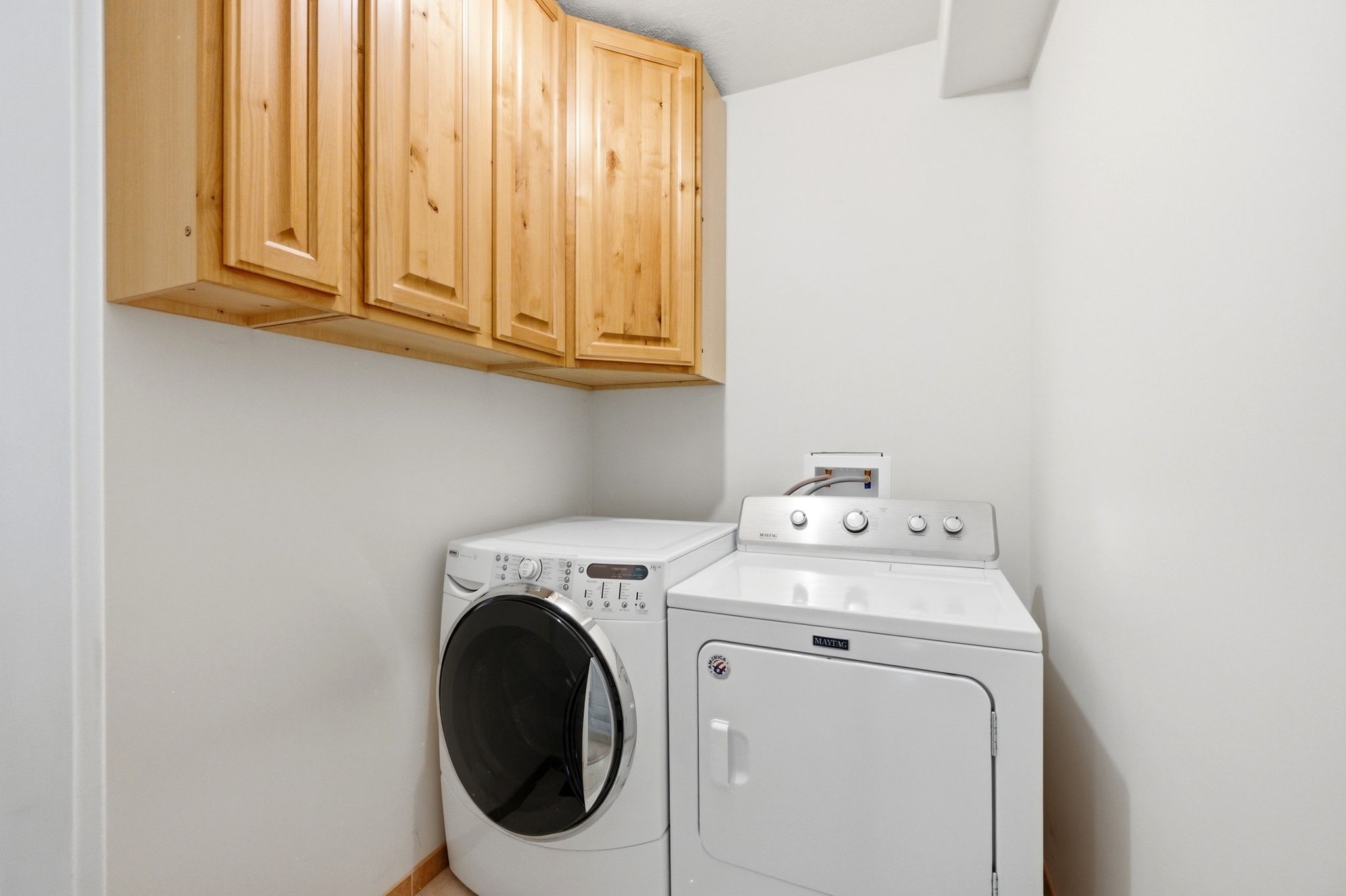 Dedicated laundry area featuring overhead natural wood cabinetry