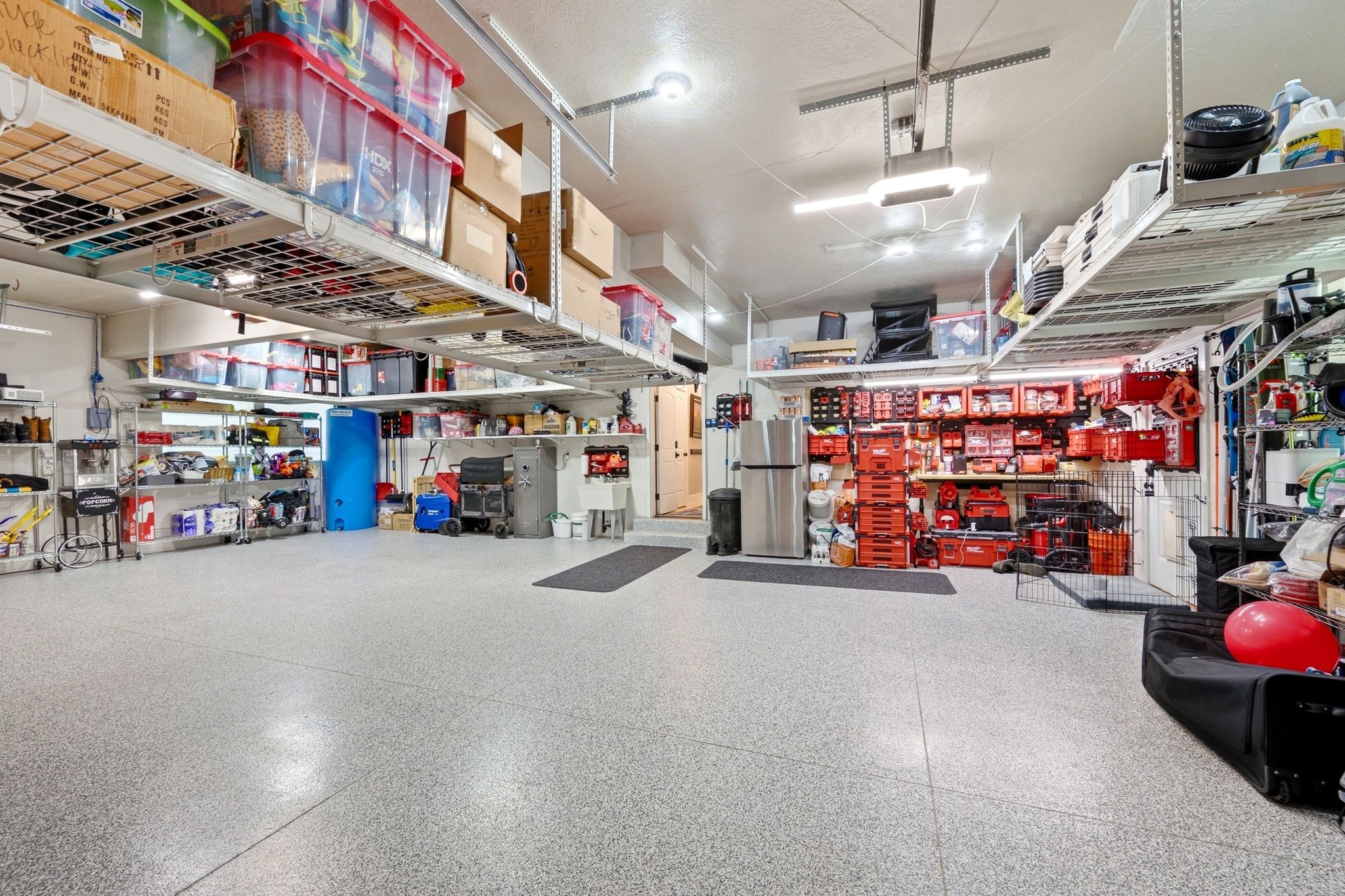 Spacious garage featuring an epoxy-coated floor, overhead storage racks, built-in shelving, and recessed lighting
