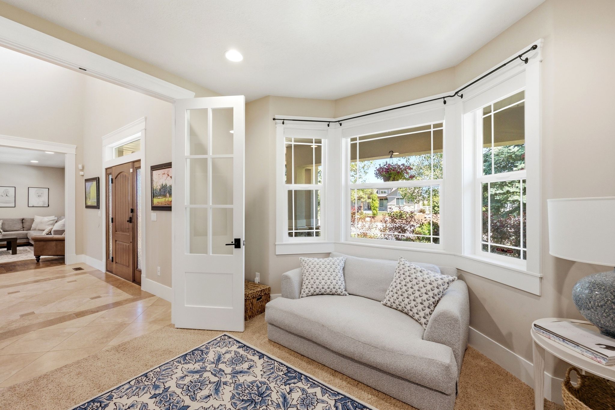 Bay window seating area with multiple windows, glass-paneled interior door, and recessed lighting