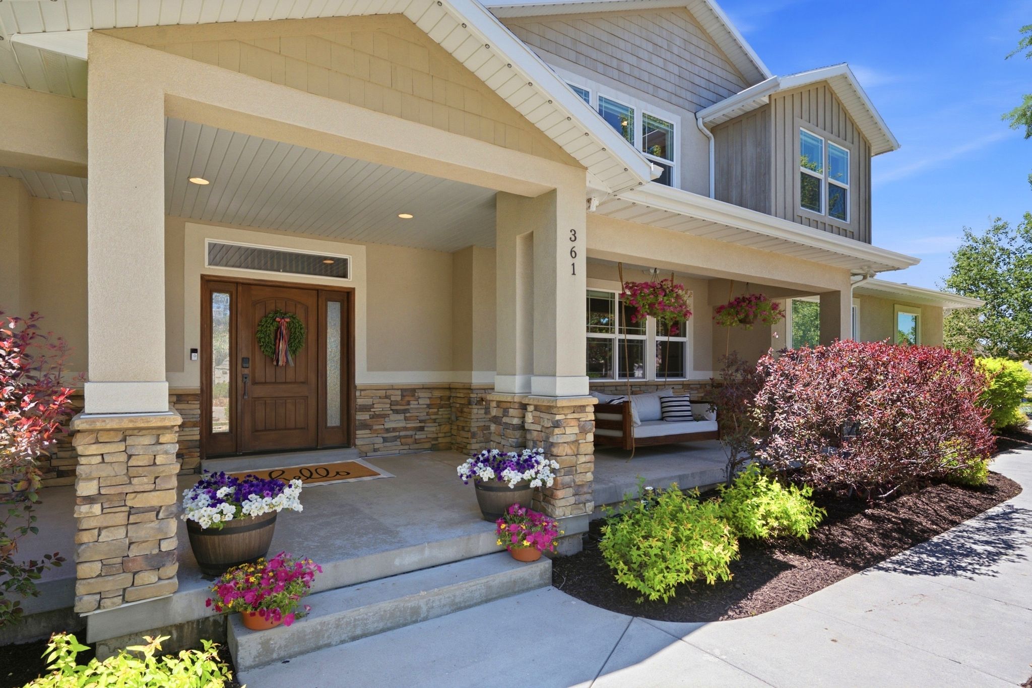 Stone and stucco exterior featuring a covered porch, wood-paneled entry door with sidelights, and recessed lighting