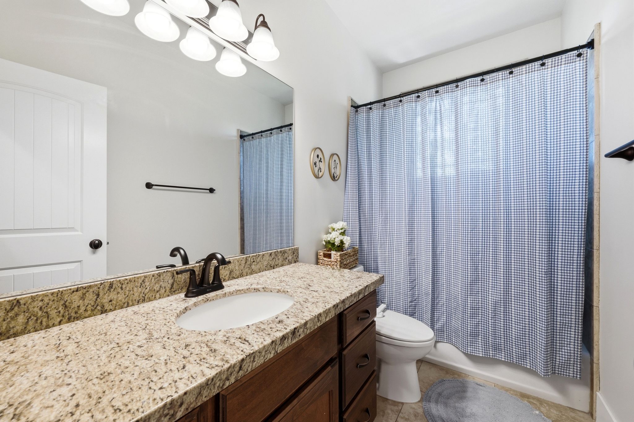 Full vanity featuring a granite countertop with an undermount sink, dark wood cabinetry, and an oil-rubbed bronze faucet