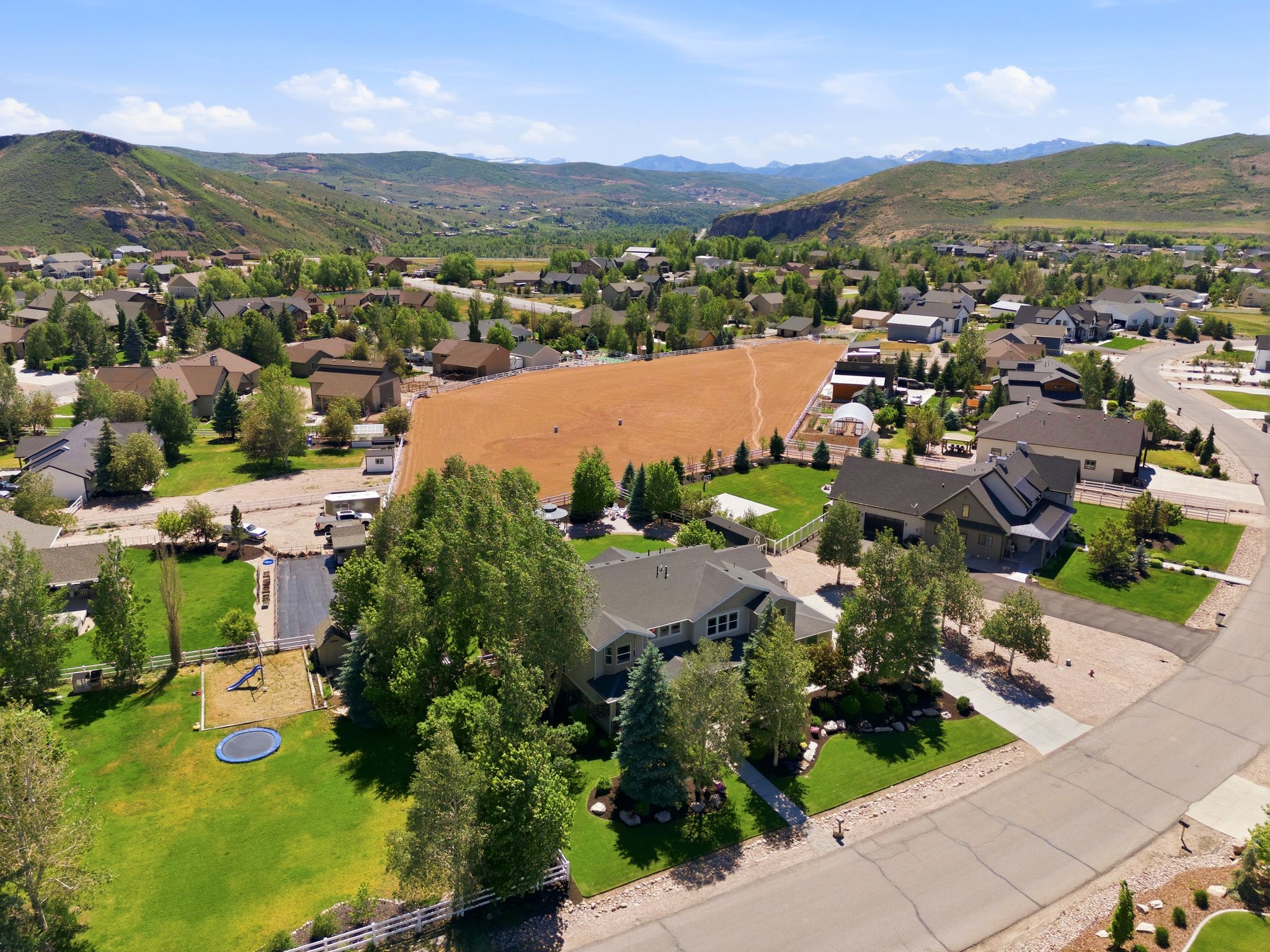 Expansive residential property featuring a large green lawn, mature trees, and a gravel driveway