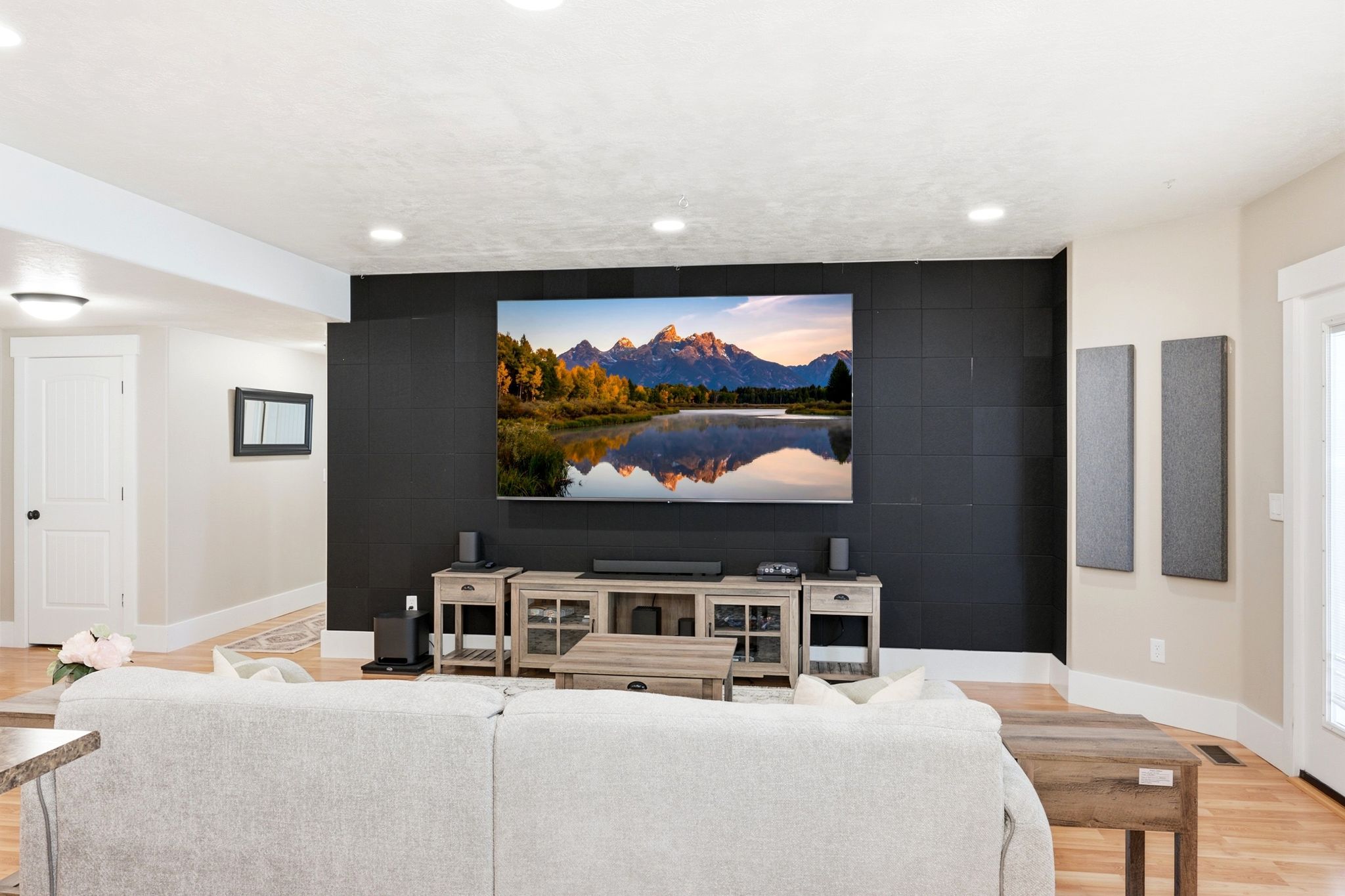 Recessed lighting illuminates a spacious room featuring wood-finish flooring and a distinctive black accent wall