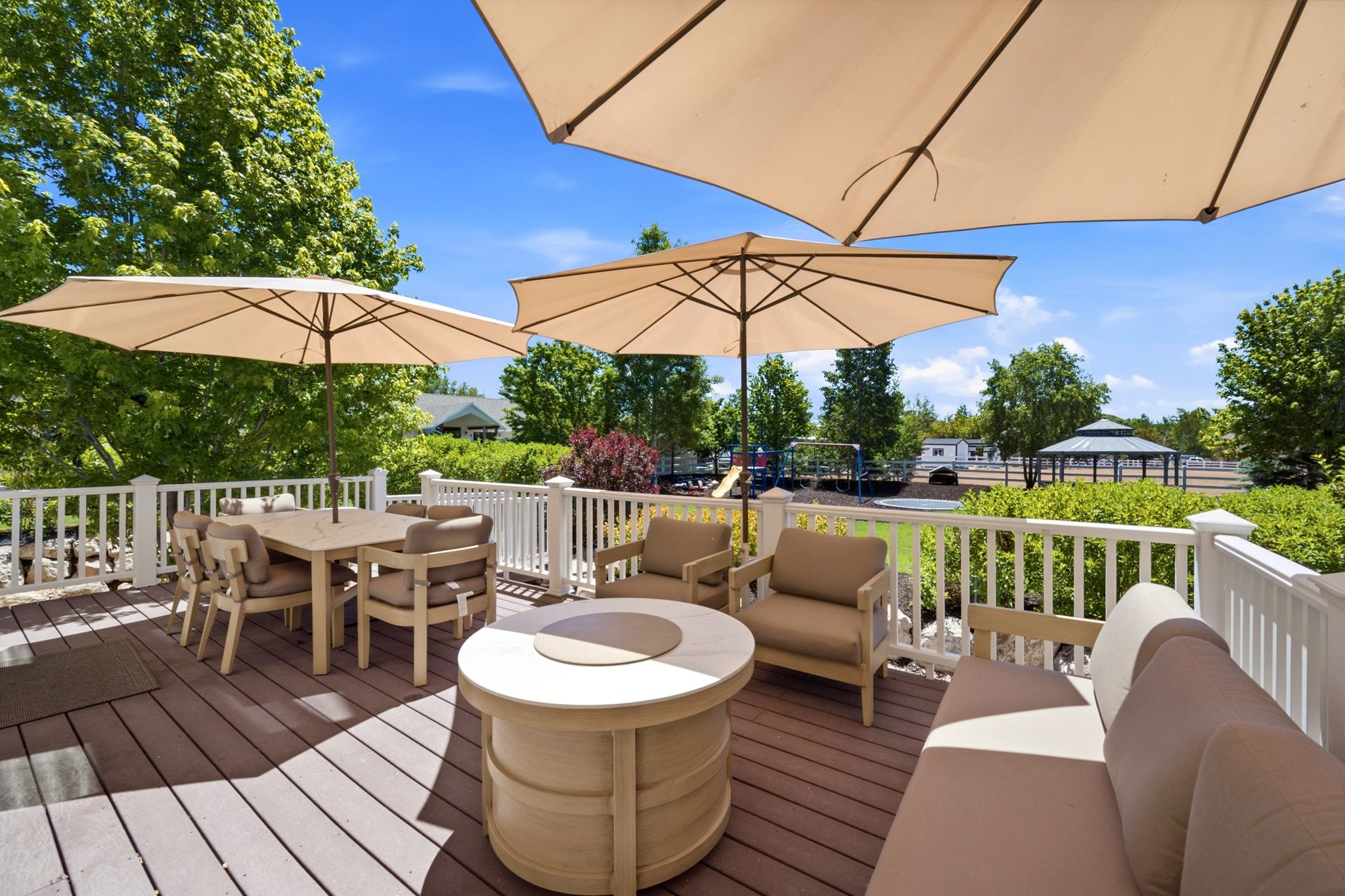 Expansive outdoor deck featuring wood-finish flooring, white railing, and a built-in fire pit