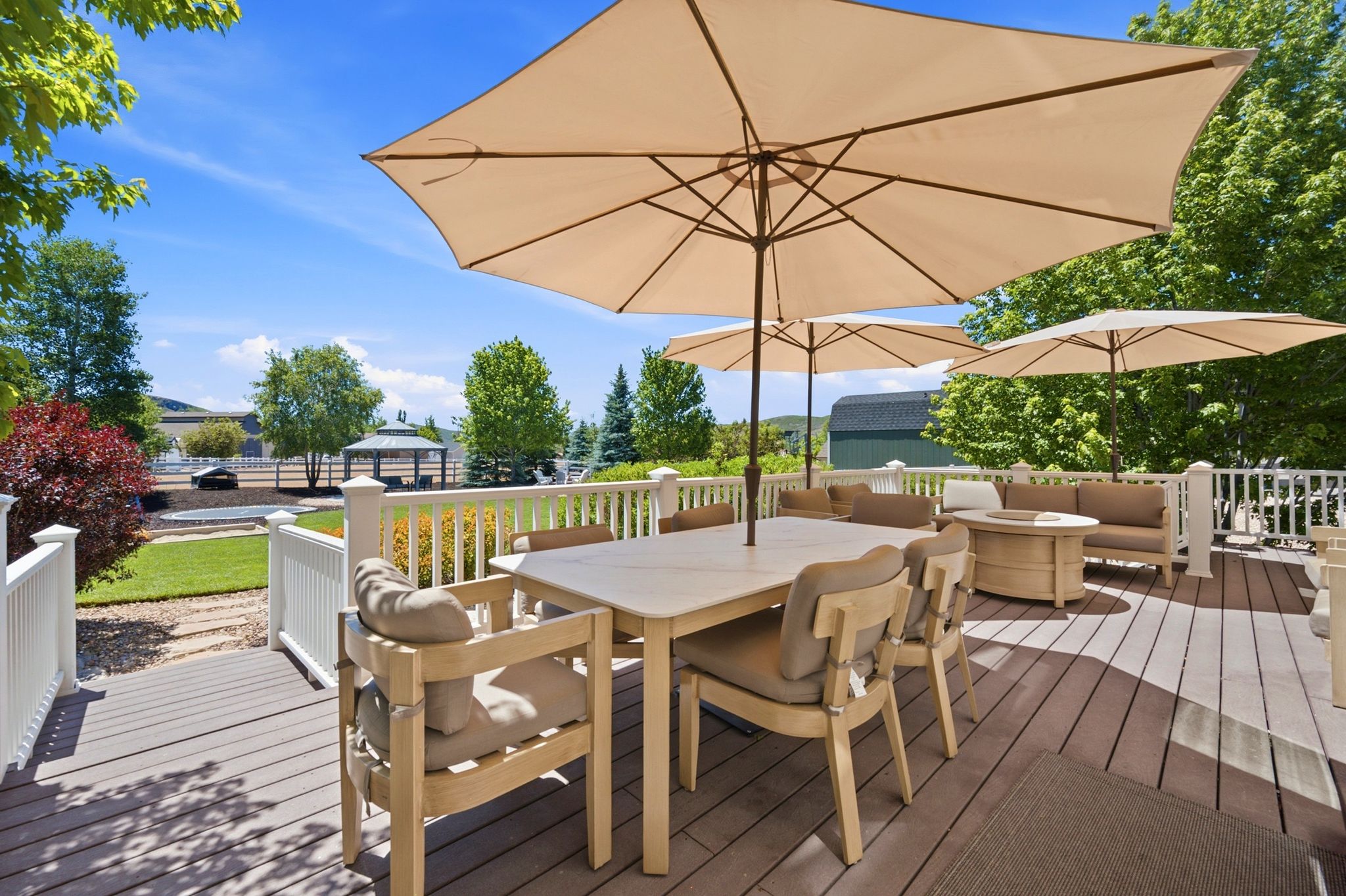 Spacious outdoor deck featuring composite decking, white railing, and a shaded dining area