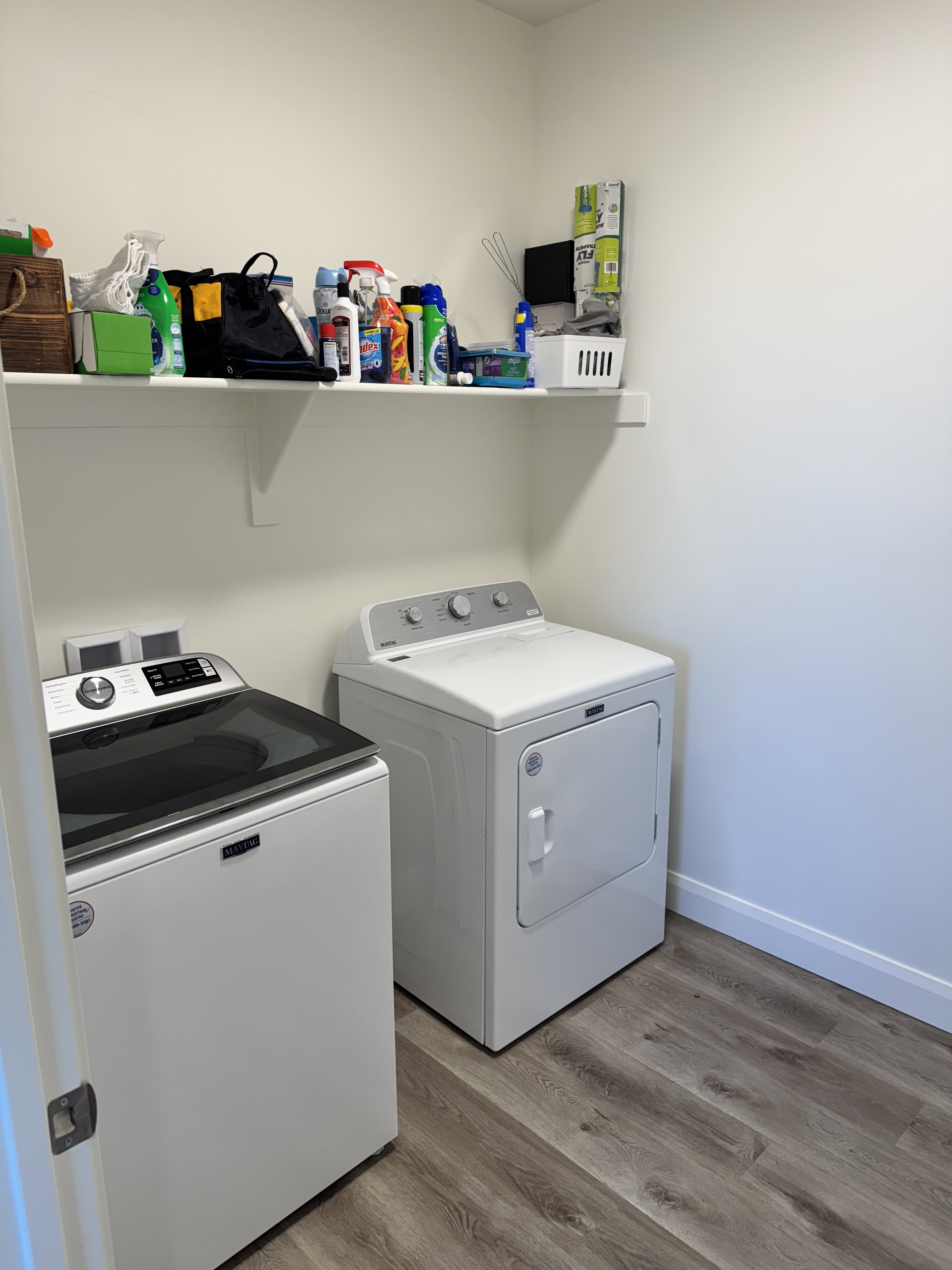Laundry area featuring wood-finish flooring and a wall-mounted storage shelf
