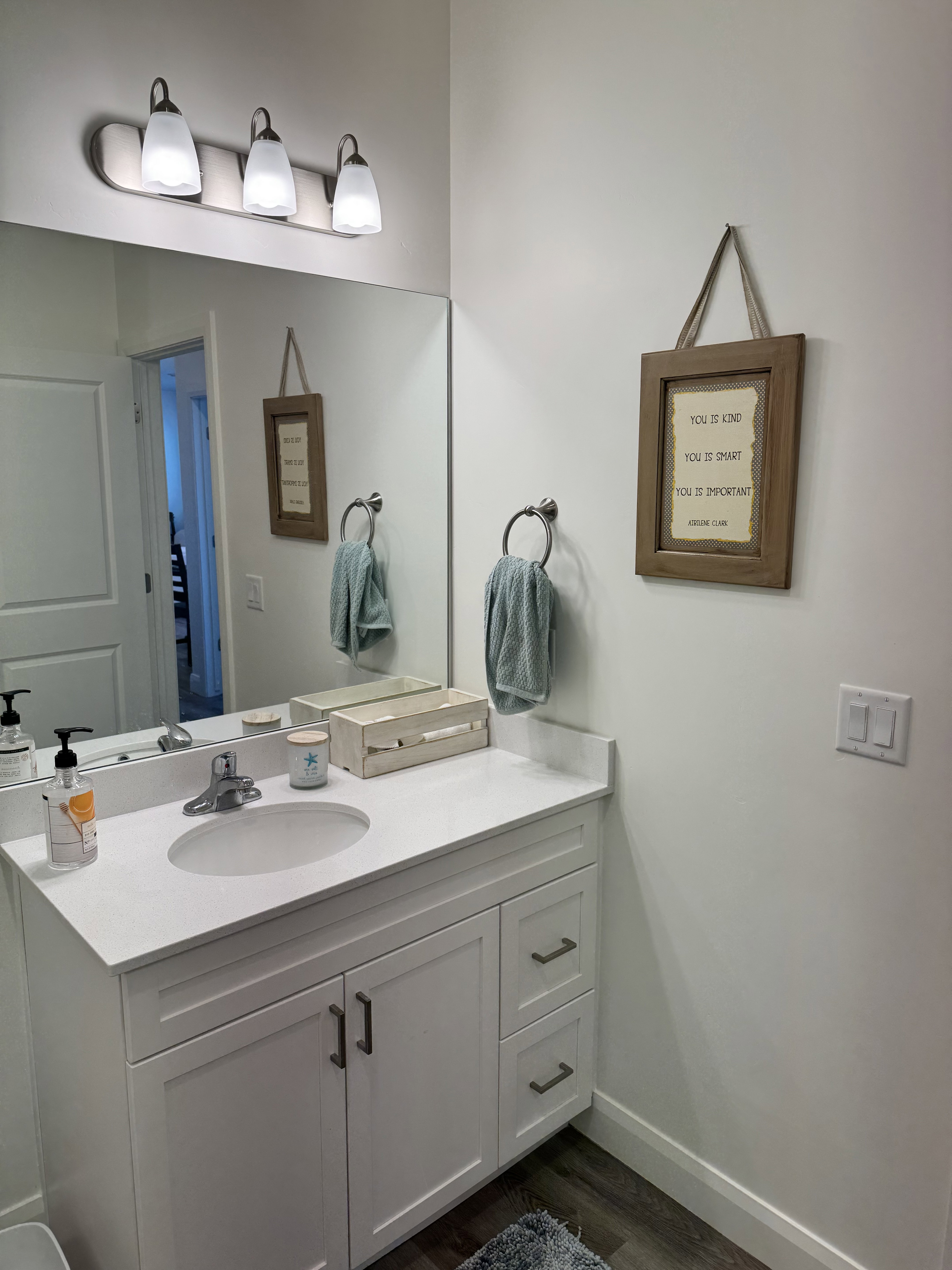 Bathroom vanity featuring a white countertop with an integrated sink, brushed nickel faucet, and white cabinetry with dark hardware