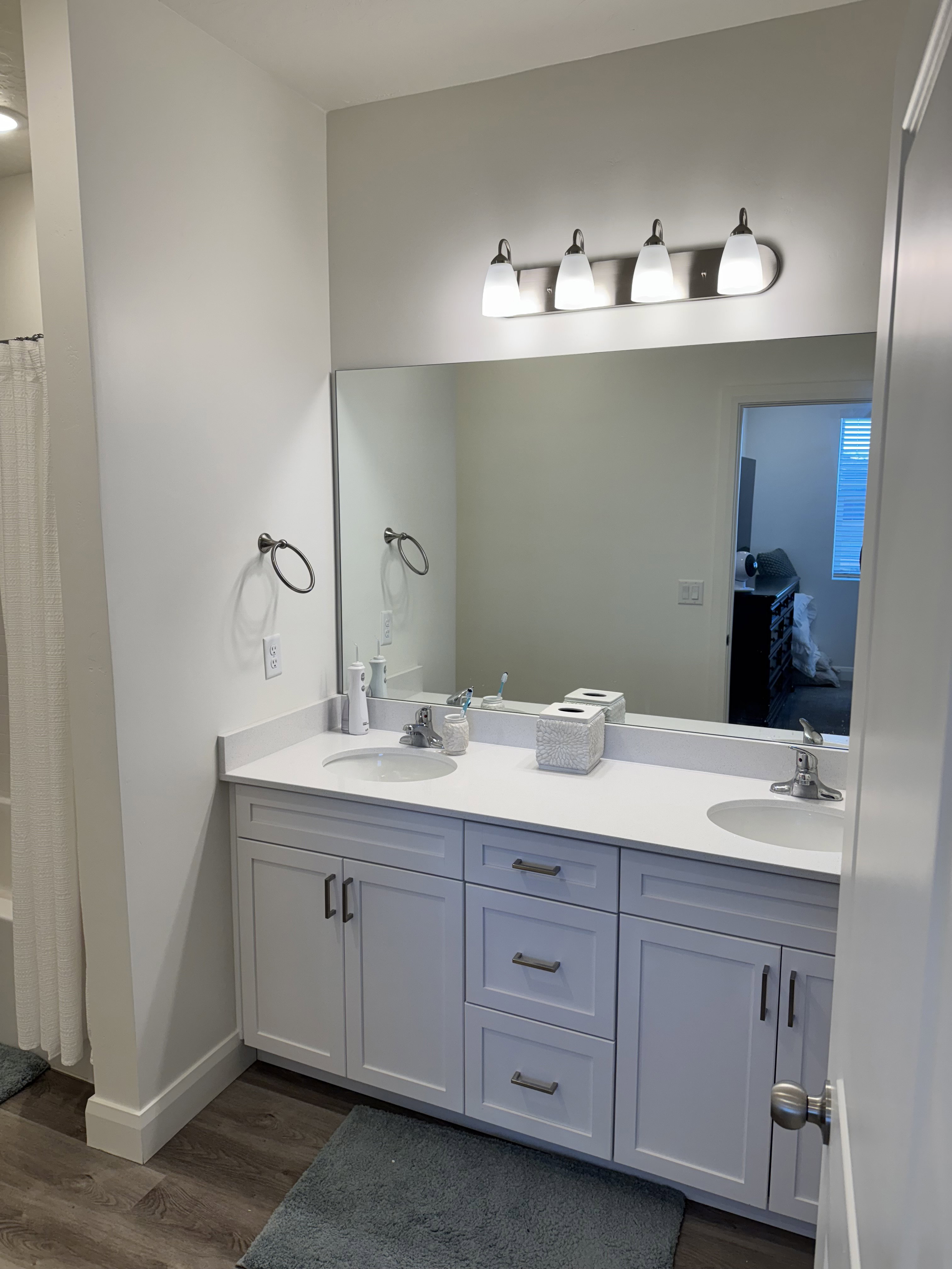 Dual vanity with undermount sinks, white countertop, and light wood-finish flooring