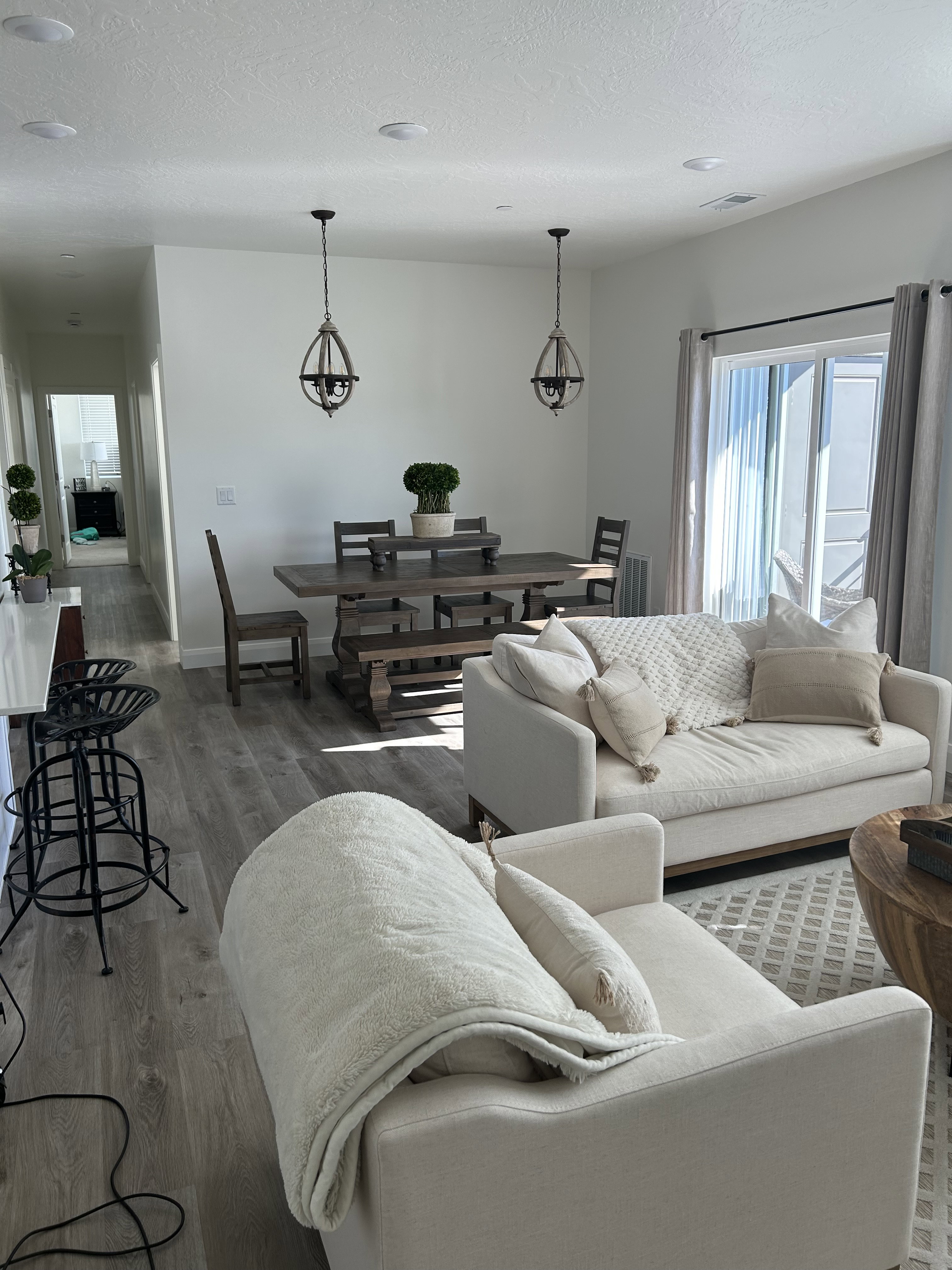 Open-concept living space featuring wood-finish flooring, recessed ceiling lights, and dual decorative pendant fixtures