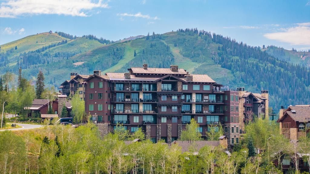 Multi-story residence featuring extensive balconies, a stone and wood facade, and a multi-gabled roofline