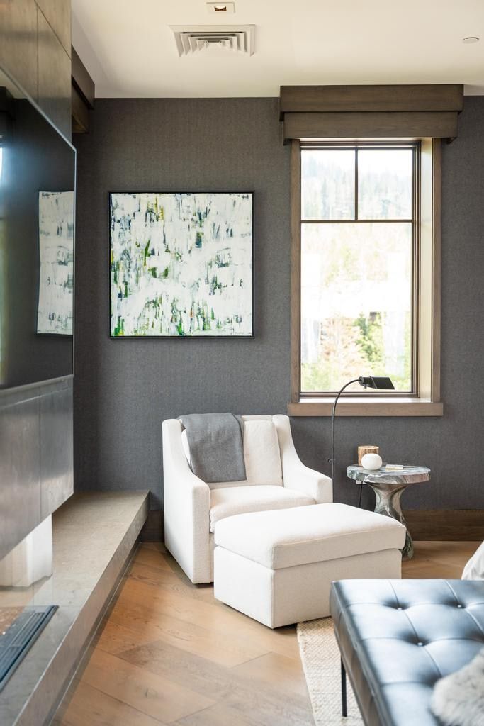Window with dark wood trim, textured dark gray walls, light wood-finish flooring, and a linear gas fireplace with a concrete hearth