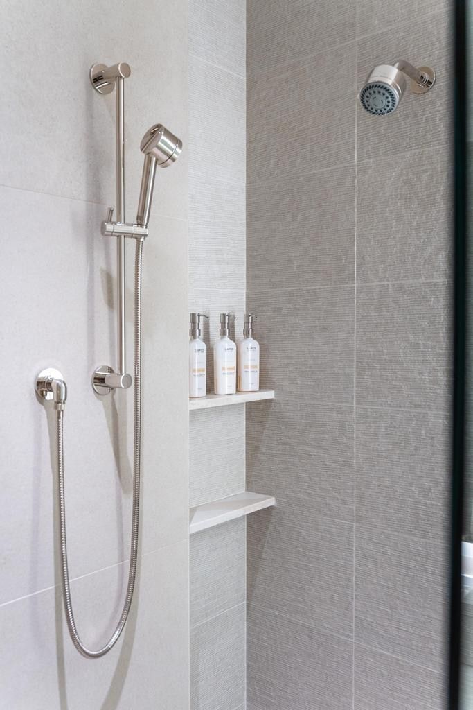 Shower with a handheld spray unit, a fixed shower head, and a recessed shelving niche