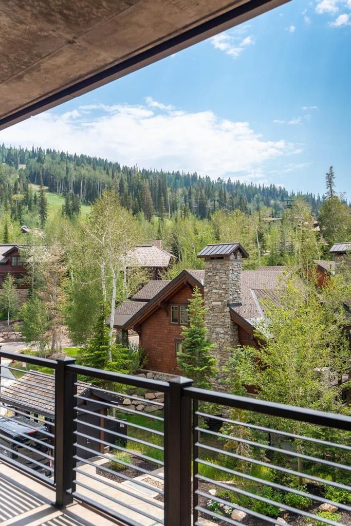 Contemporary exterior balcony with metal railing, showcasing surrounding mountainous terrain and distant architectural elements