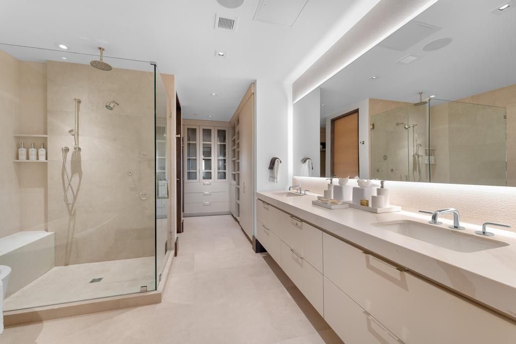 Spacious bathroom featuring a frameless glass shower enclosure with rain shower head and integrated bench