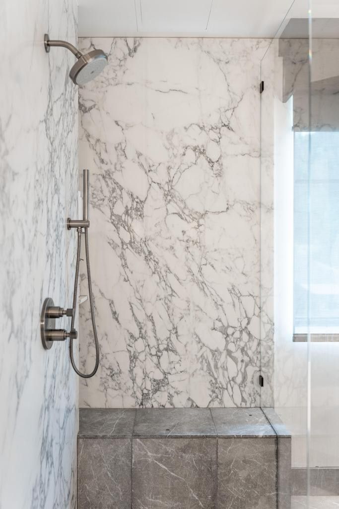 Shower with full-height stone slab surround, brushed nickel fixtures, built-in stone bench, and glass enclosure