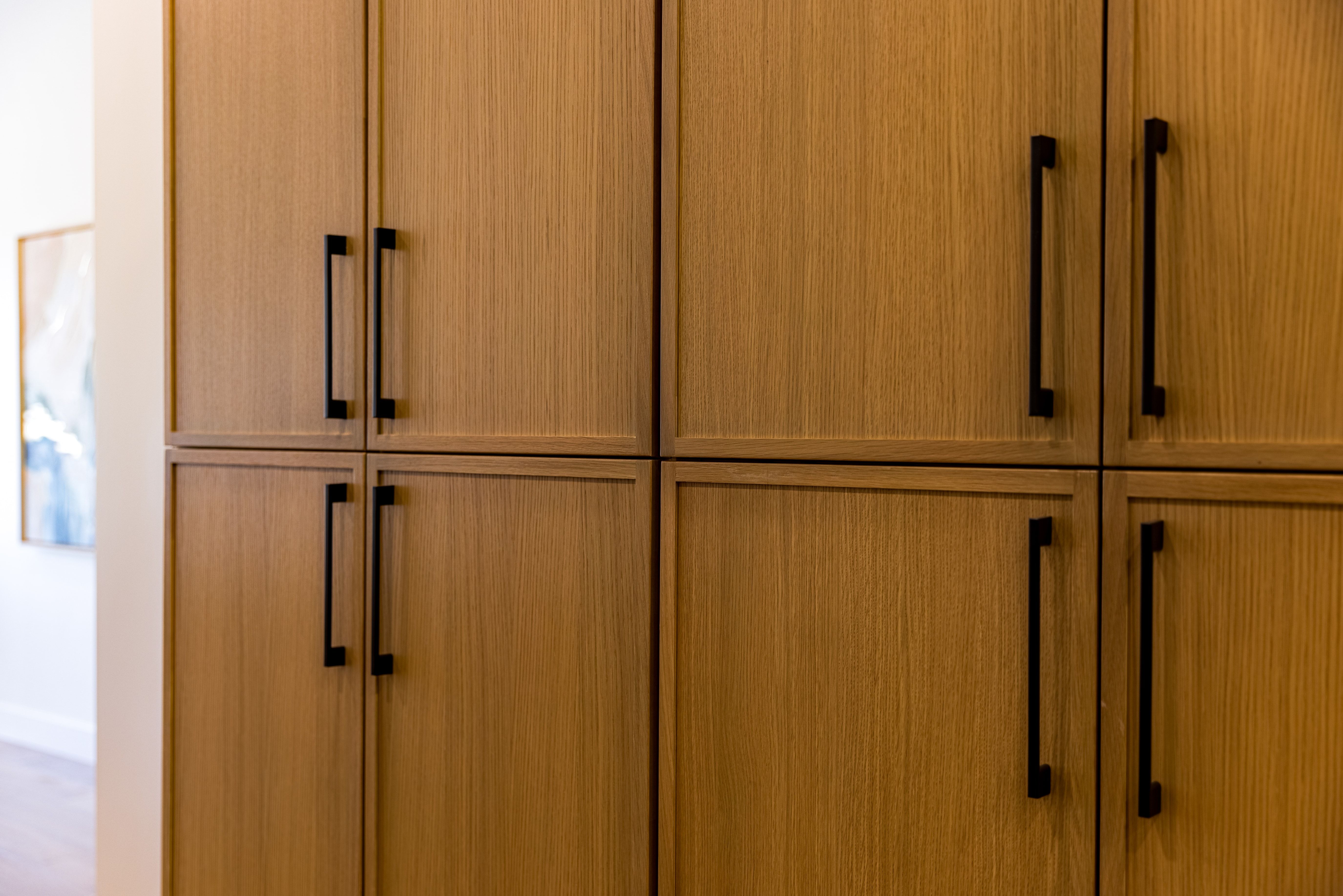 Custom built-in cabinetry with a light wood-finish and matte black hardware