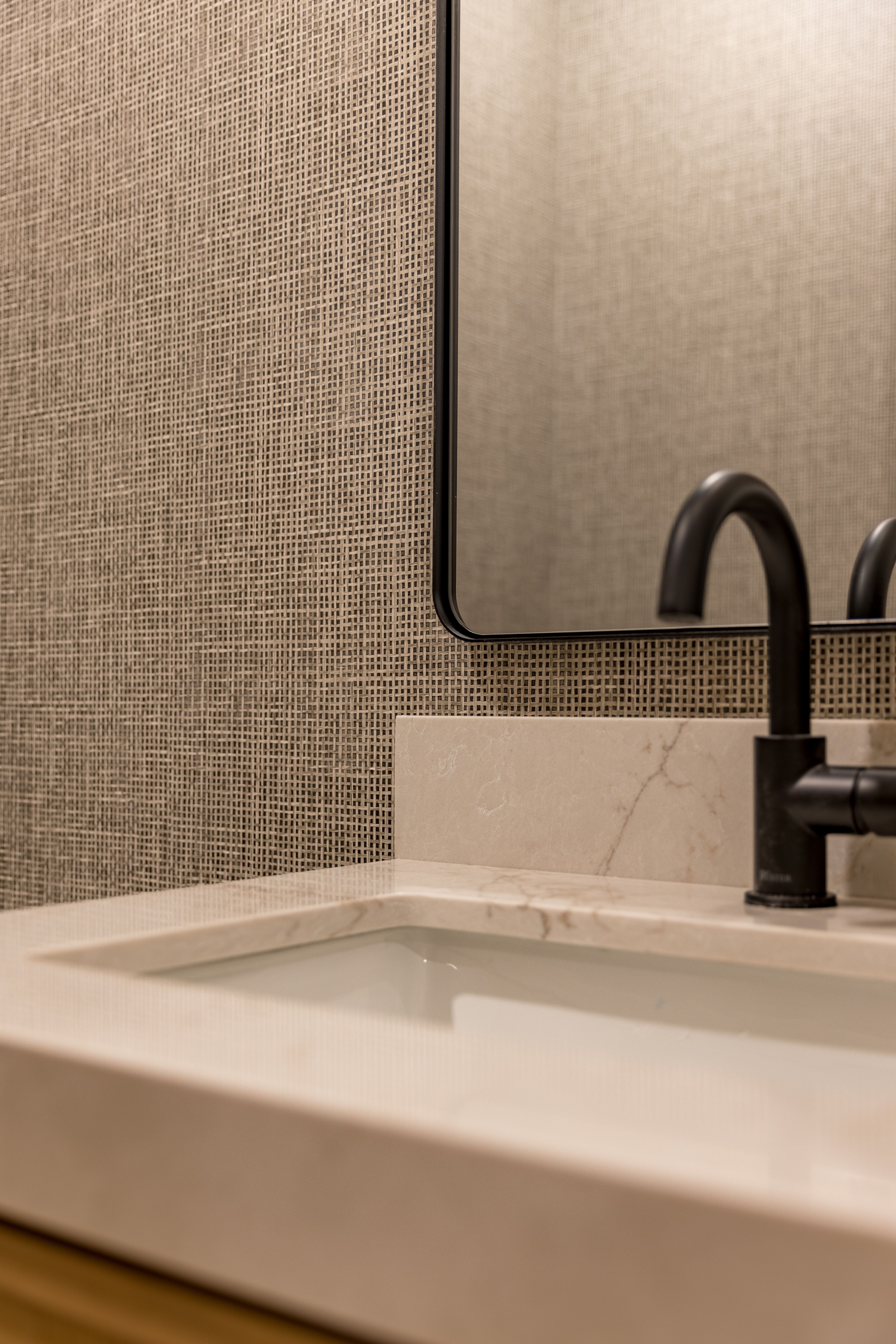 Integrated rectangular sink with a light-toned countertop, matte black faucet, and a black-framed mirror