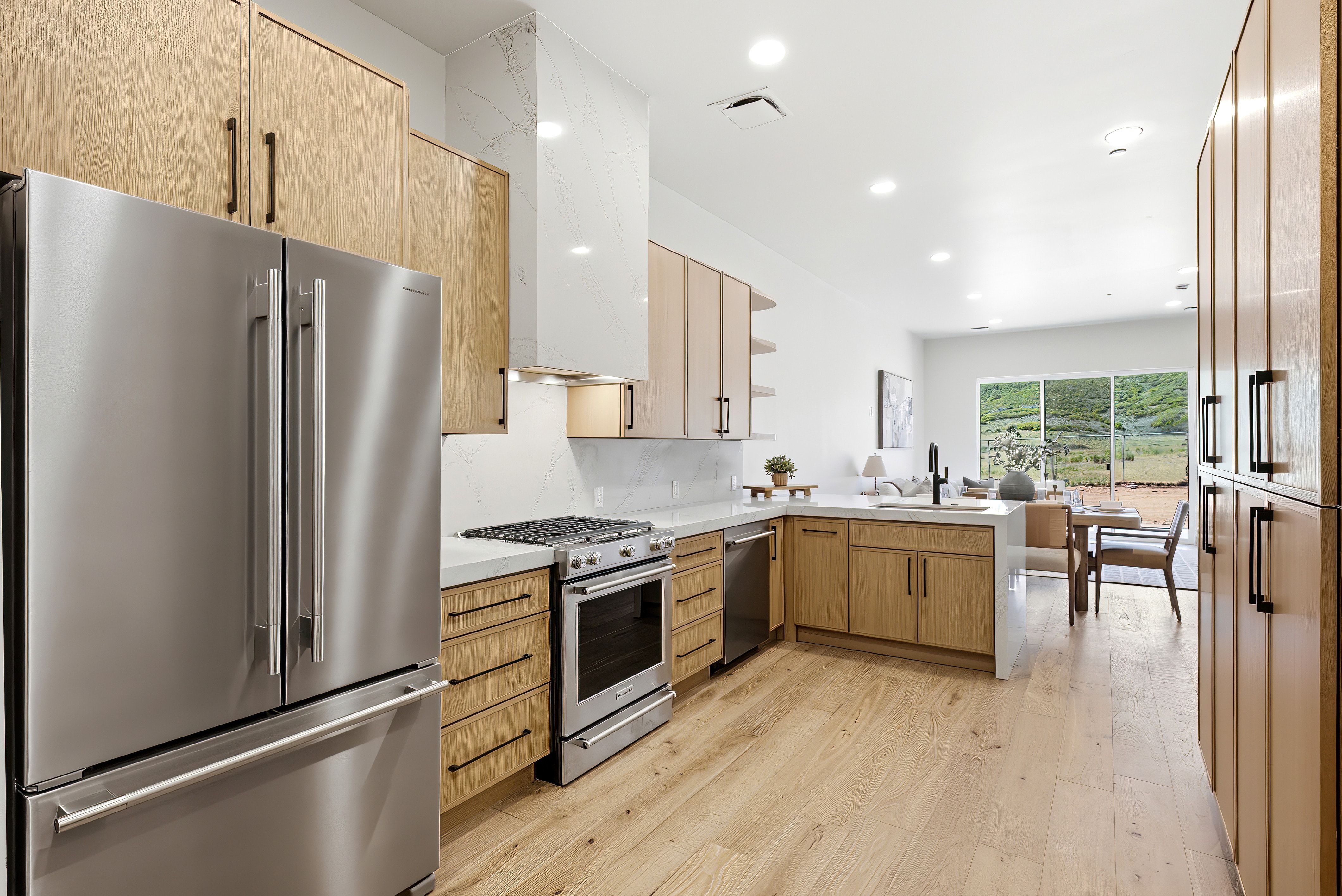 Modern kitchen featuring light wood-finish cabinetry, stainless steel appliances, a gas range, white countertops, and wood-finish flooring