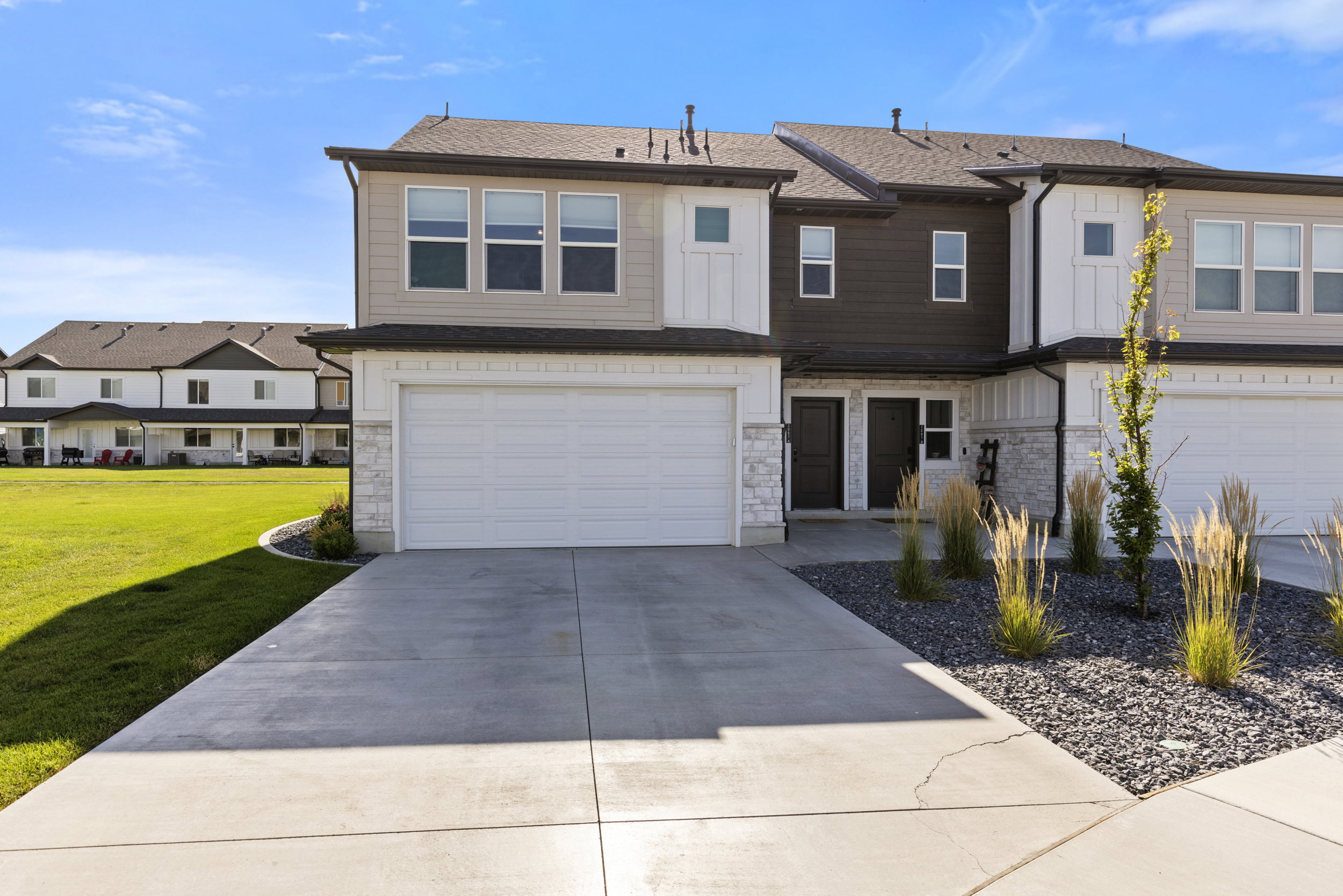 Contemporary townhome featuring a two-car garage, concrete driveway, and stone accents