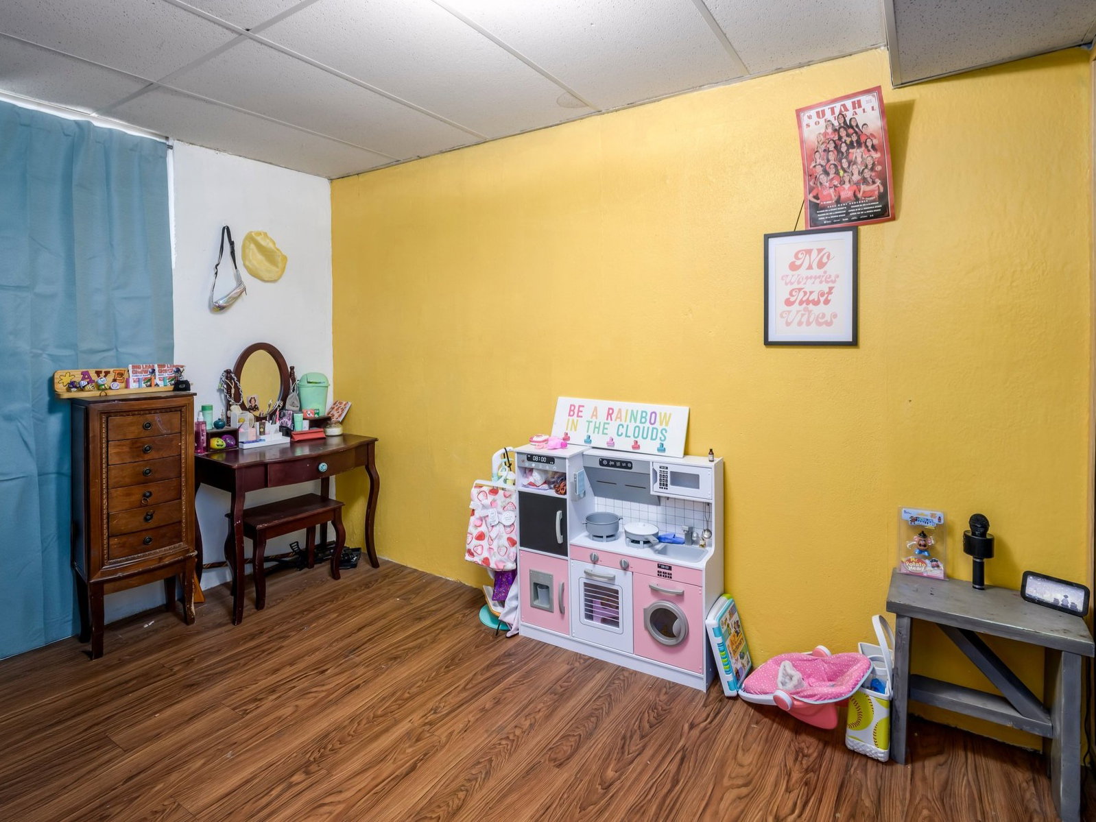 Room featuring wood-finish flooring, a drop ceiling, and bright yellow wall accents