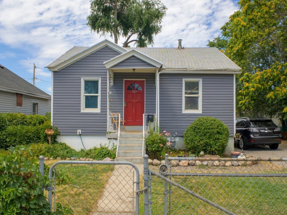 Siding exterior with a red front door, white trim, and a gabled roofline