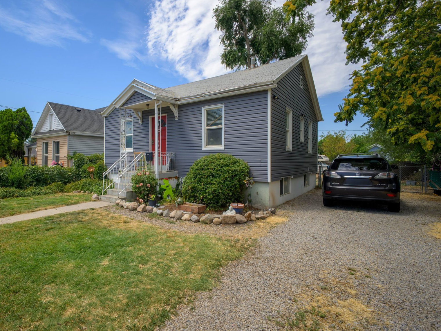 Exterior siding in a subdued tone with a red entry door, white trim, and a covered porch