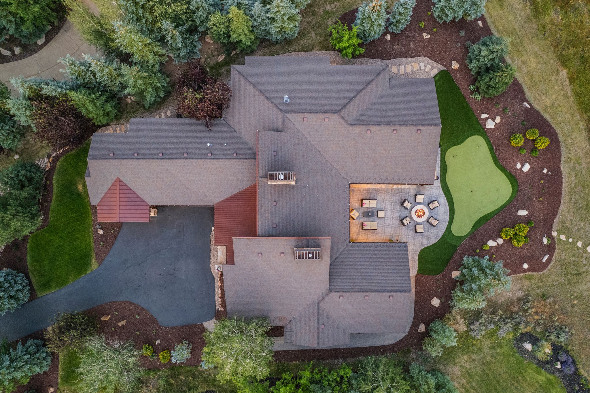 Expansive property showcasing a multi-level asphalt shingle roof, a paved driveway, and a red metal-roofed portico