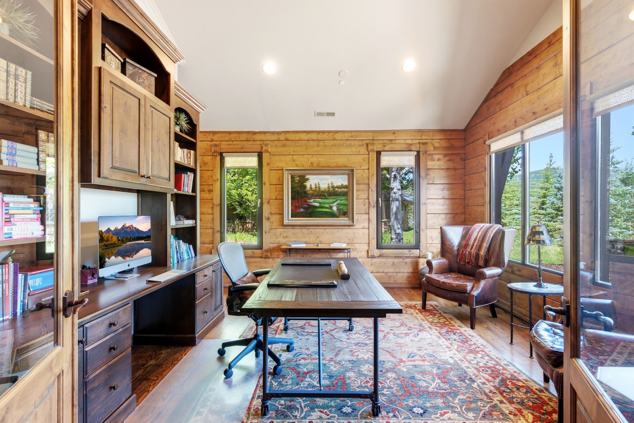 Wood-paneled room featuring extensive built-in cabinetry, wood-finish flooring, and multiple windows