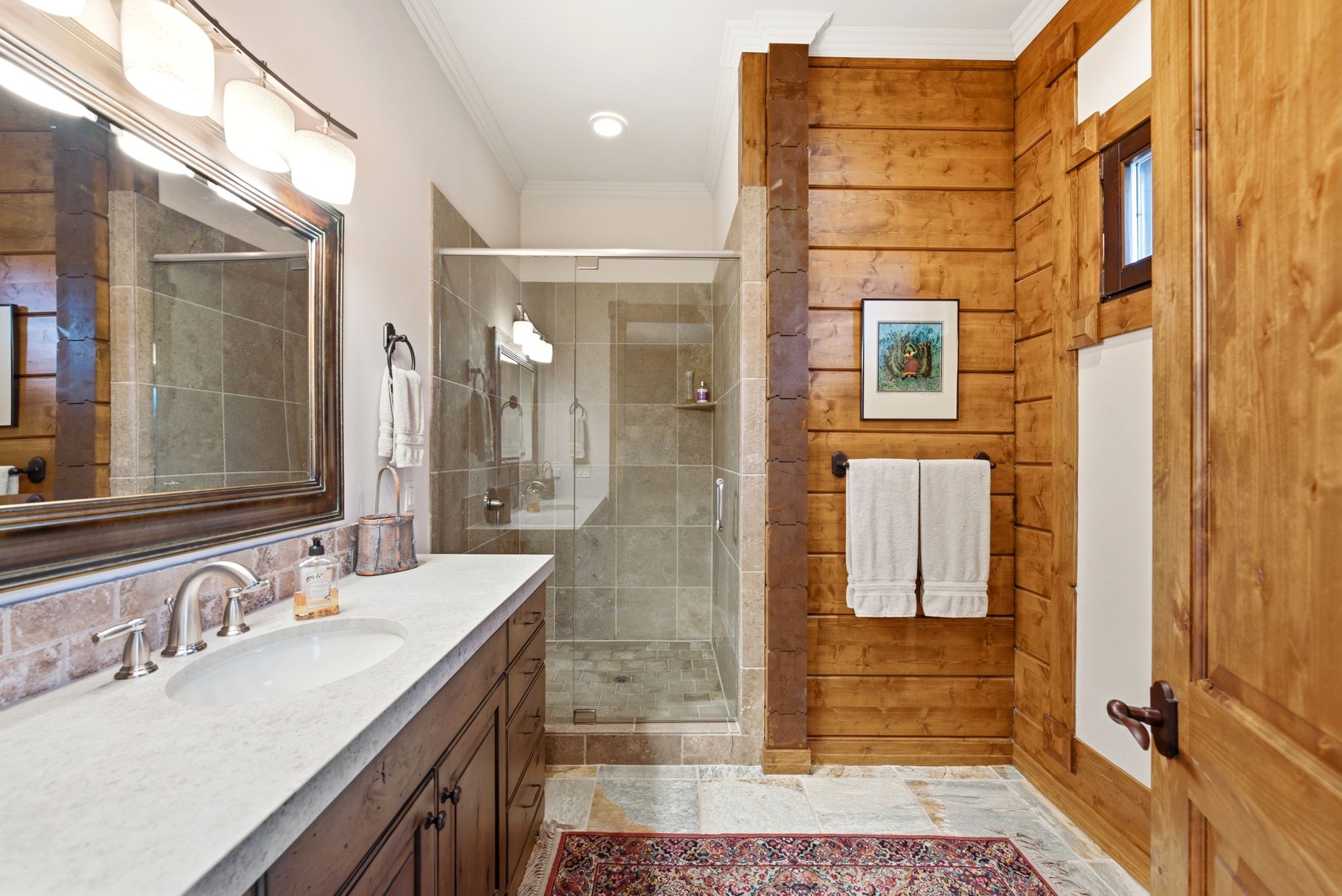 Bathroom featuring a wood-finish vanity with a light-toned countertop and an undermount sink