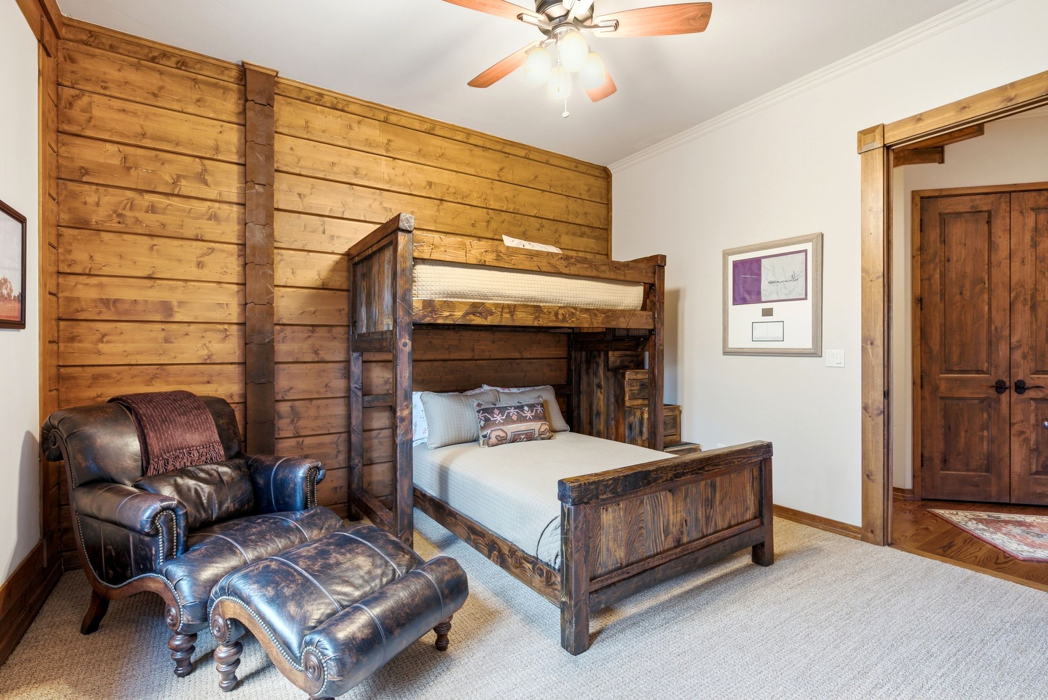 Room featuring wood-plank accent wall, wood-finish trim, and wood-finish double doors