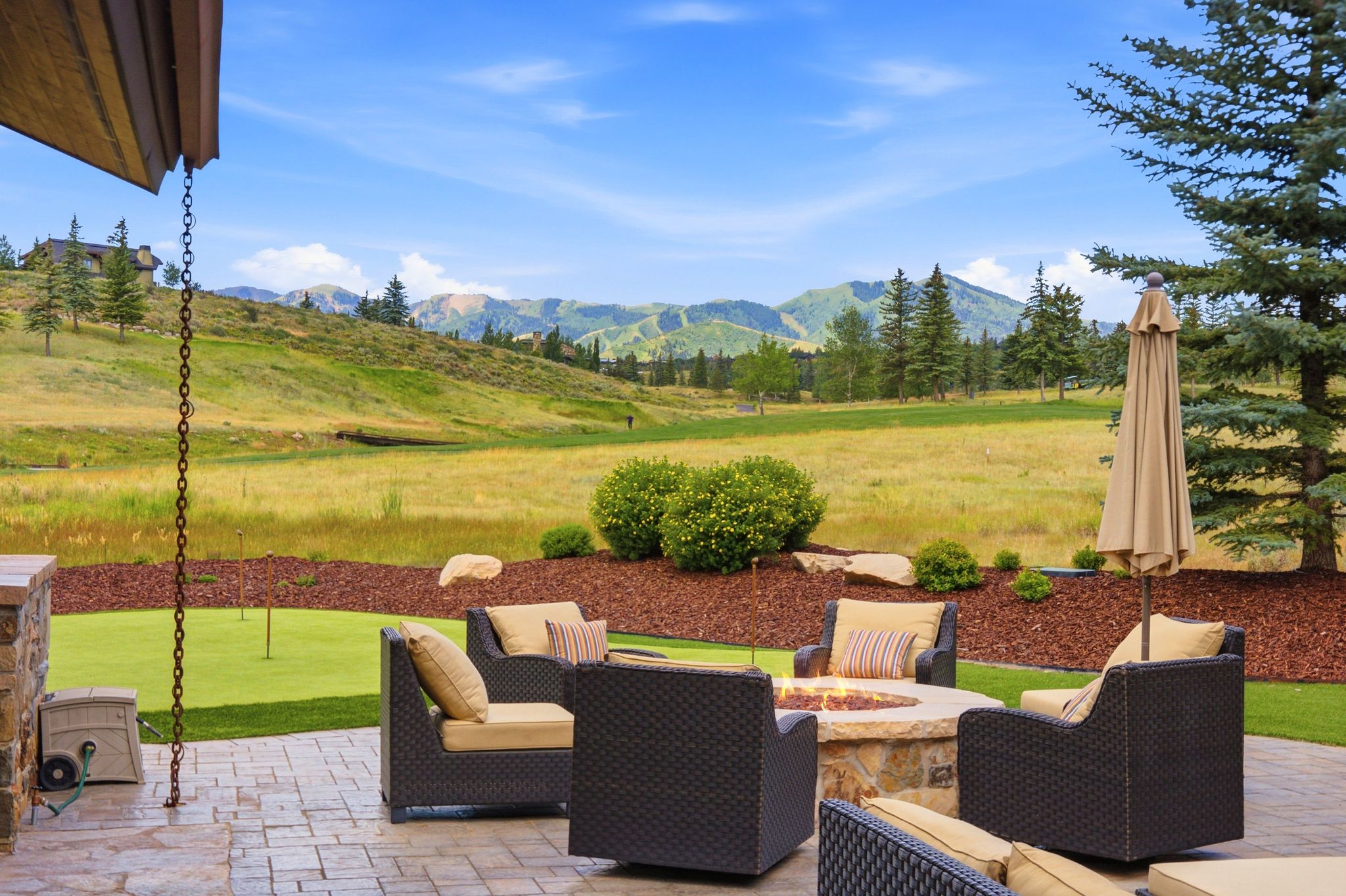 Expansive outdoor patio featuring a stone-clad fire pit and stamped concrete pavers