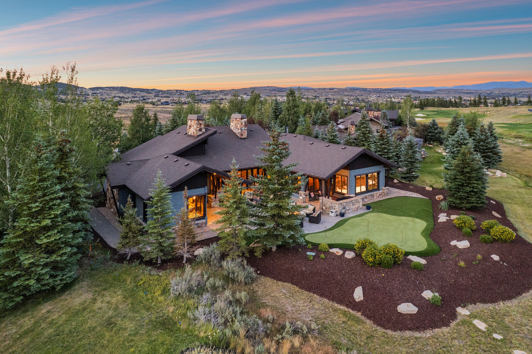 Contemporary residence featuring a dark roof, multiple stone chimneys, and expansive windows