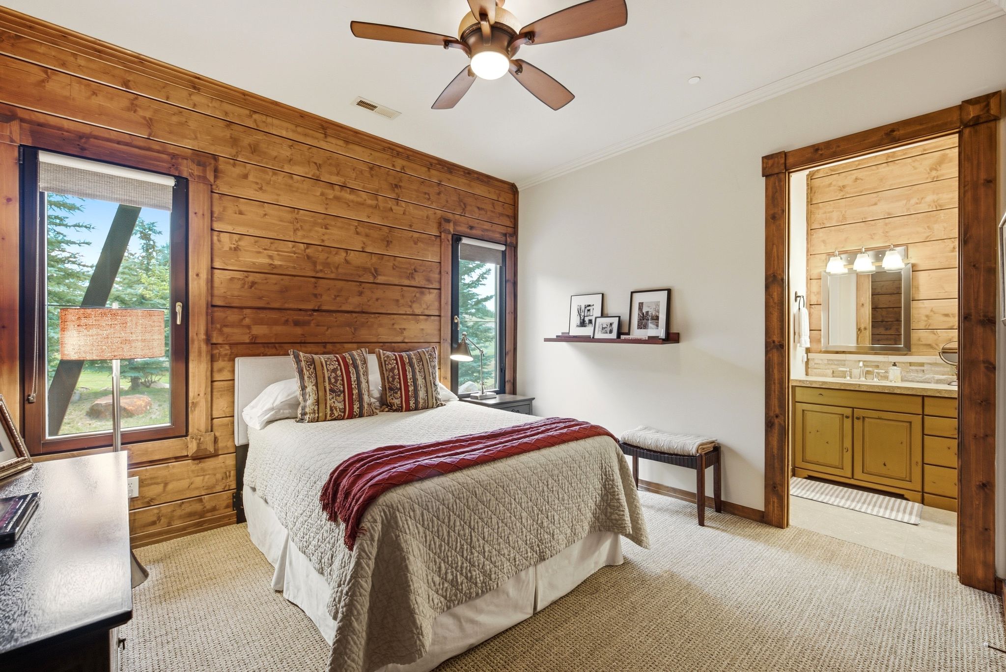 Bedroom featuring extensive wood-paneled walls and a ceiling fan