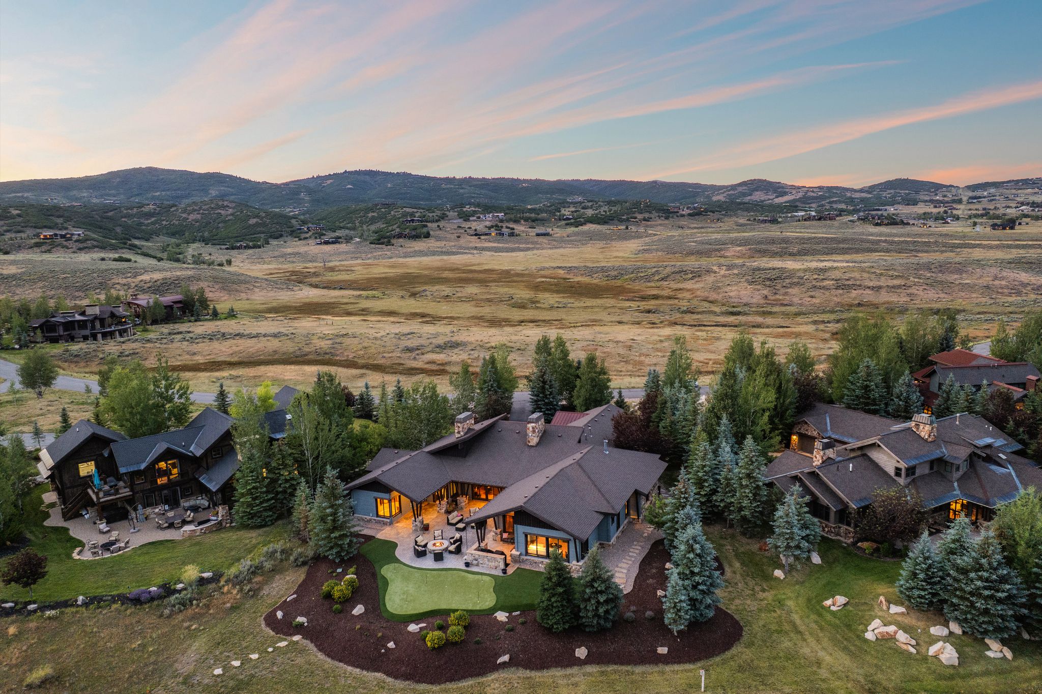 Expansive property featuring a putting green, multiple patios, and mature landscaping