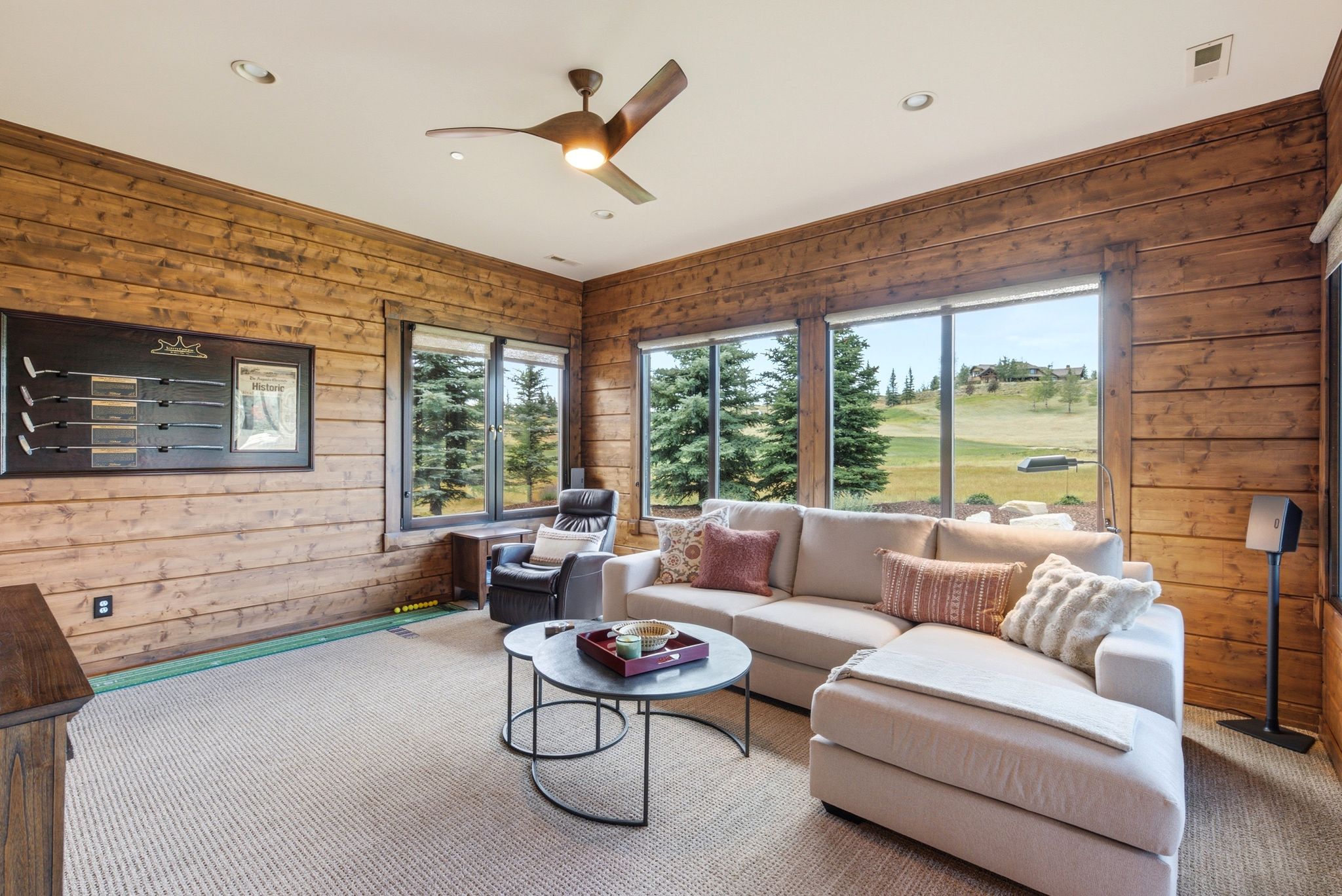 Spacious living area featuring extensive wood-finish wall paneling, recessed lighting, and a modern ceiling fan