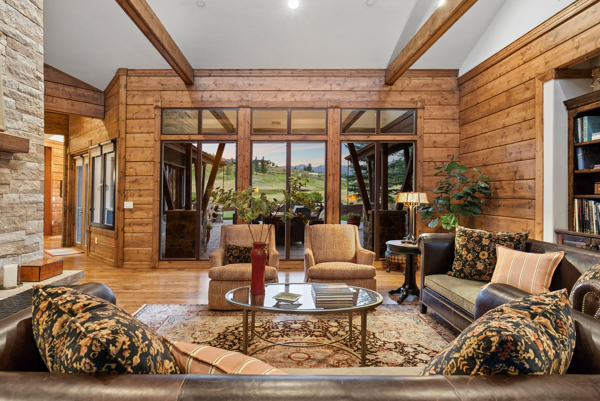 Expansive living area featuring wood-finish flooring, exposed ceiling beams, and horizontal wood paneling