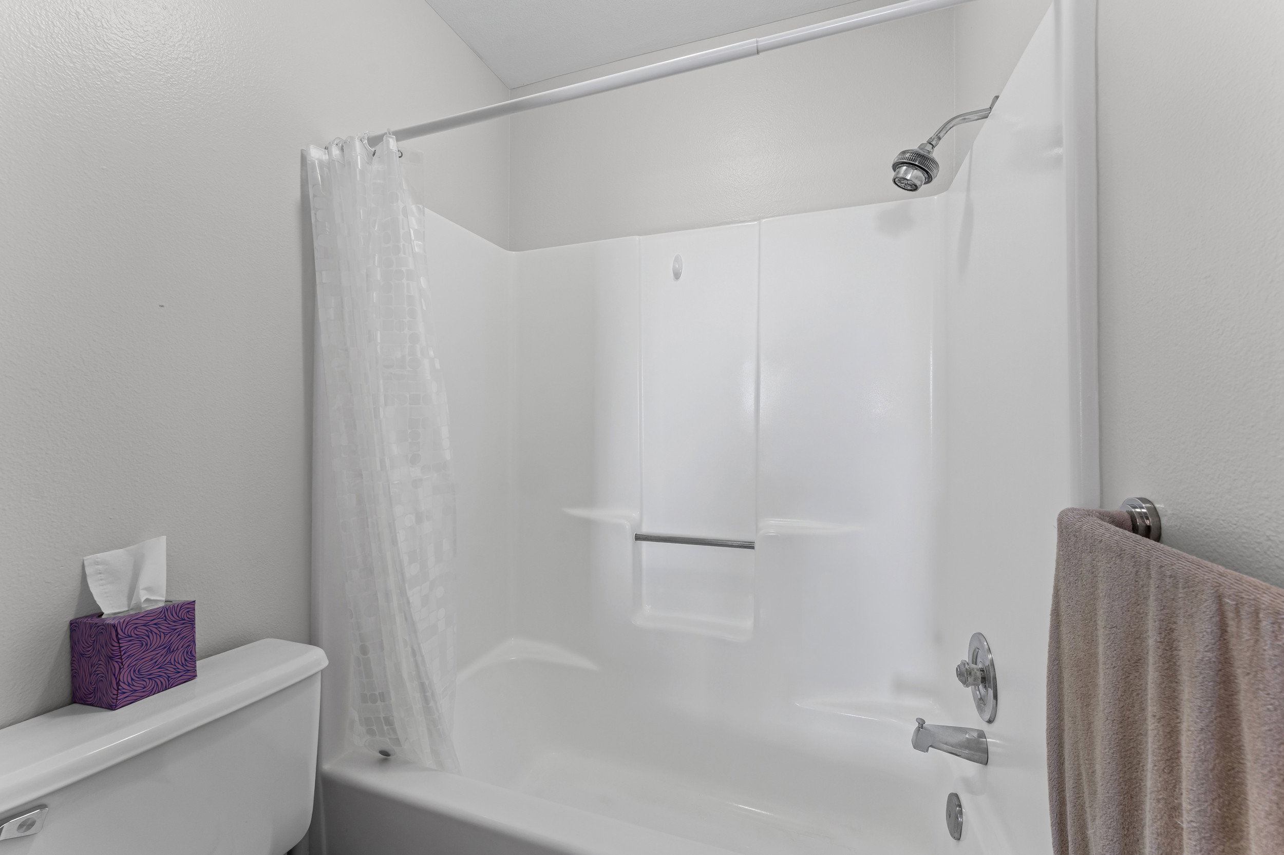 White acrylic tub/shower combination featuring chrome fixtures