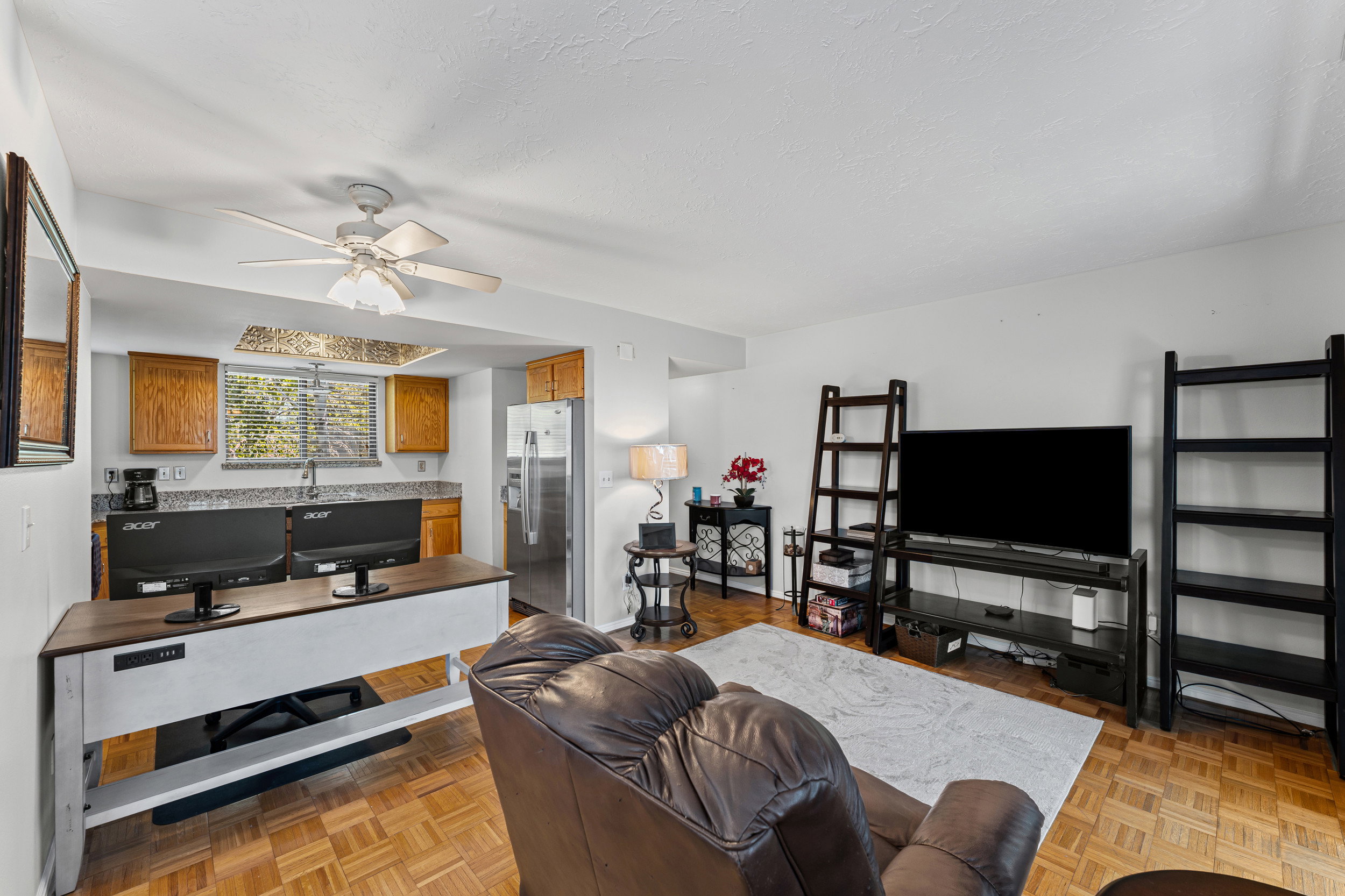Open-concept living space with wood-finish flooring, a ceiling fan, and white walls